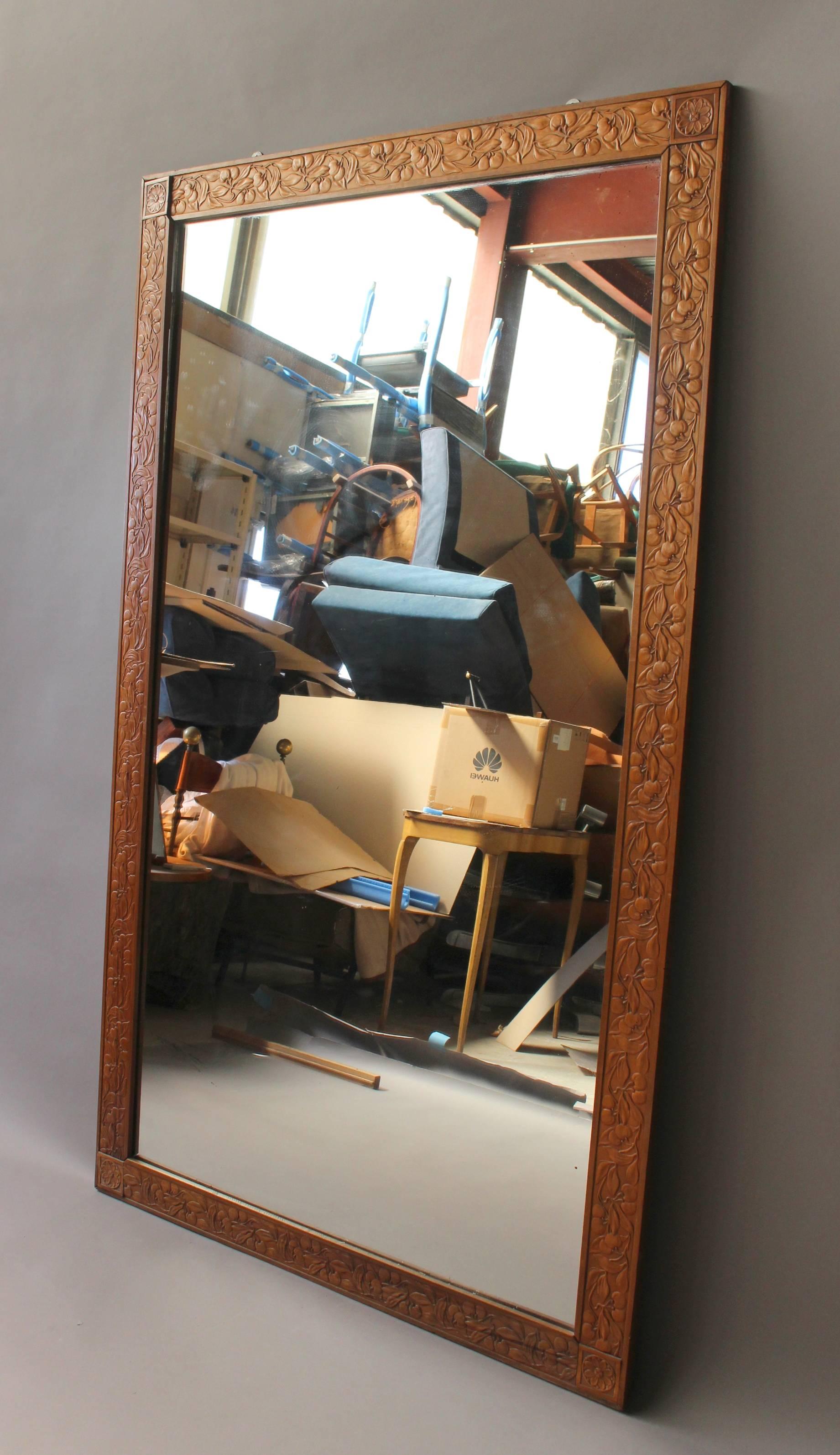 A large French Art Deco floral embossed pear-wood framed mirror.