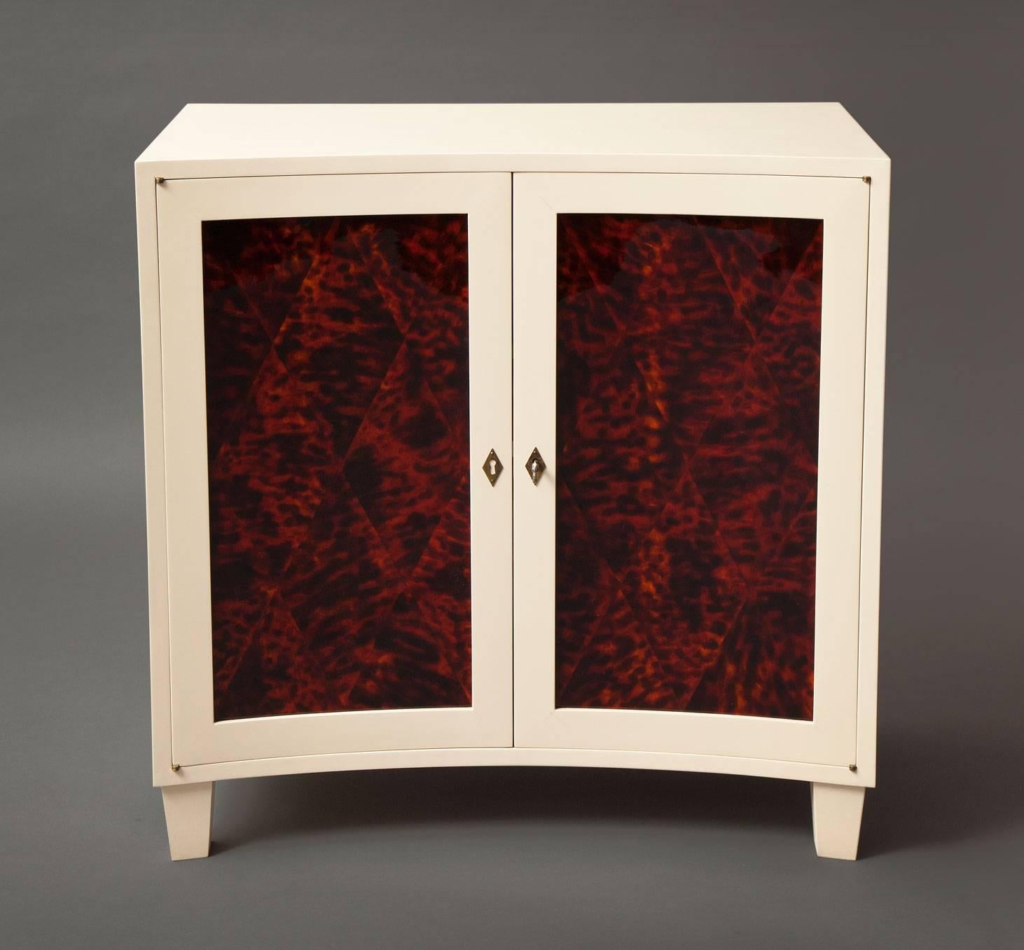 The two-door cabinet
Curved front two-door cabinet in a satin linen color
finish with inset decorative painted doors. 
Raised on tapering block feet.
Doors open to reveal three shelves. 
Custom sizes and faux finishes, including tortoiseshell
