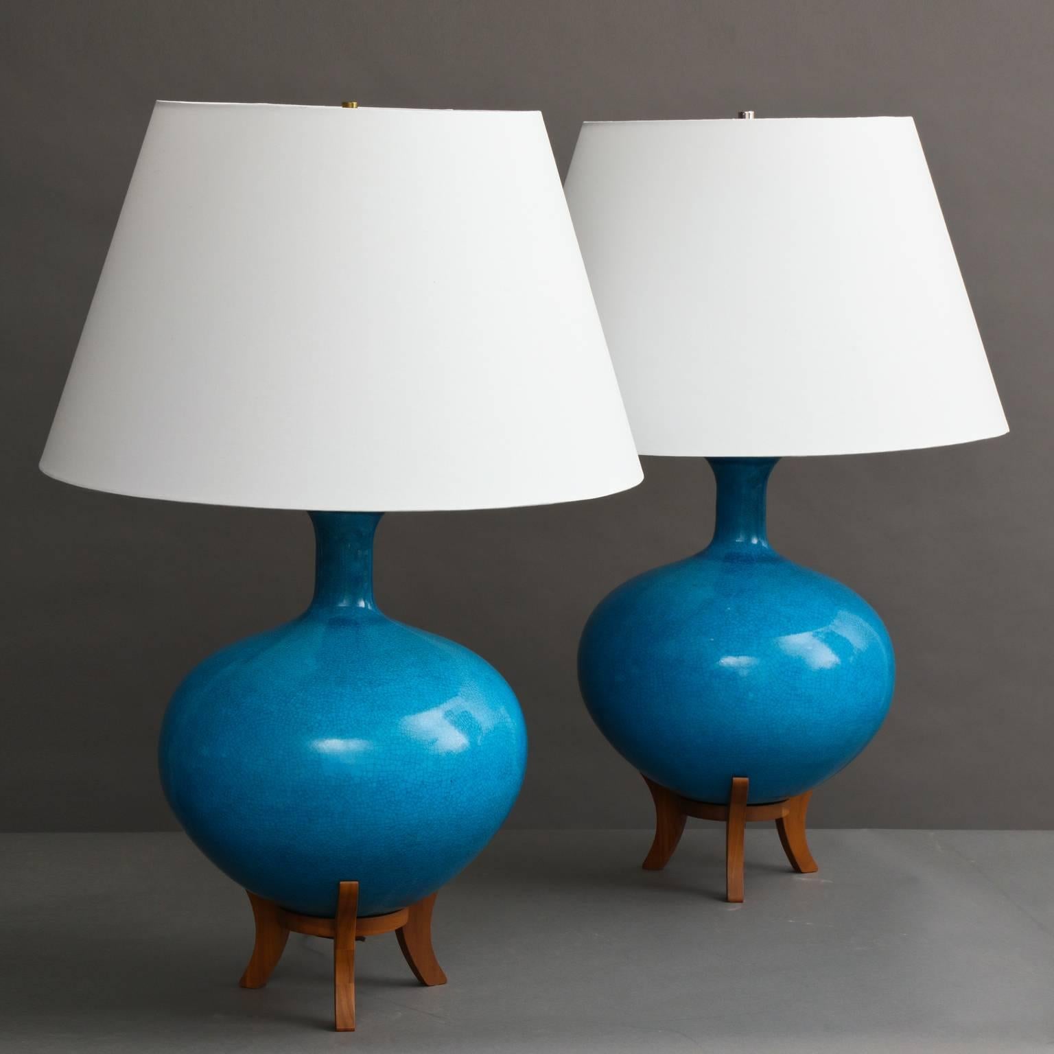 Pair of large ceramic lamps in a crackled rich turquoise blue glaze mounted on teak wood bases with curved feet. Lampshades not included.
American, circa 1950.
Measures: 22.5