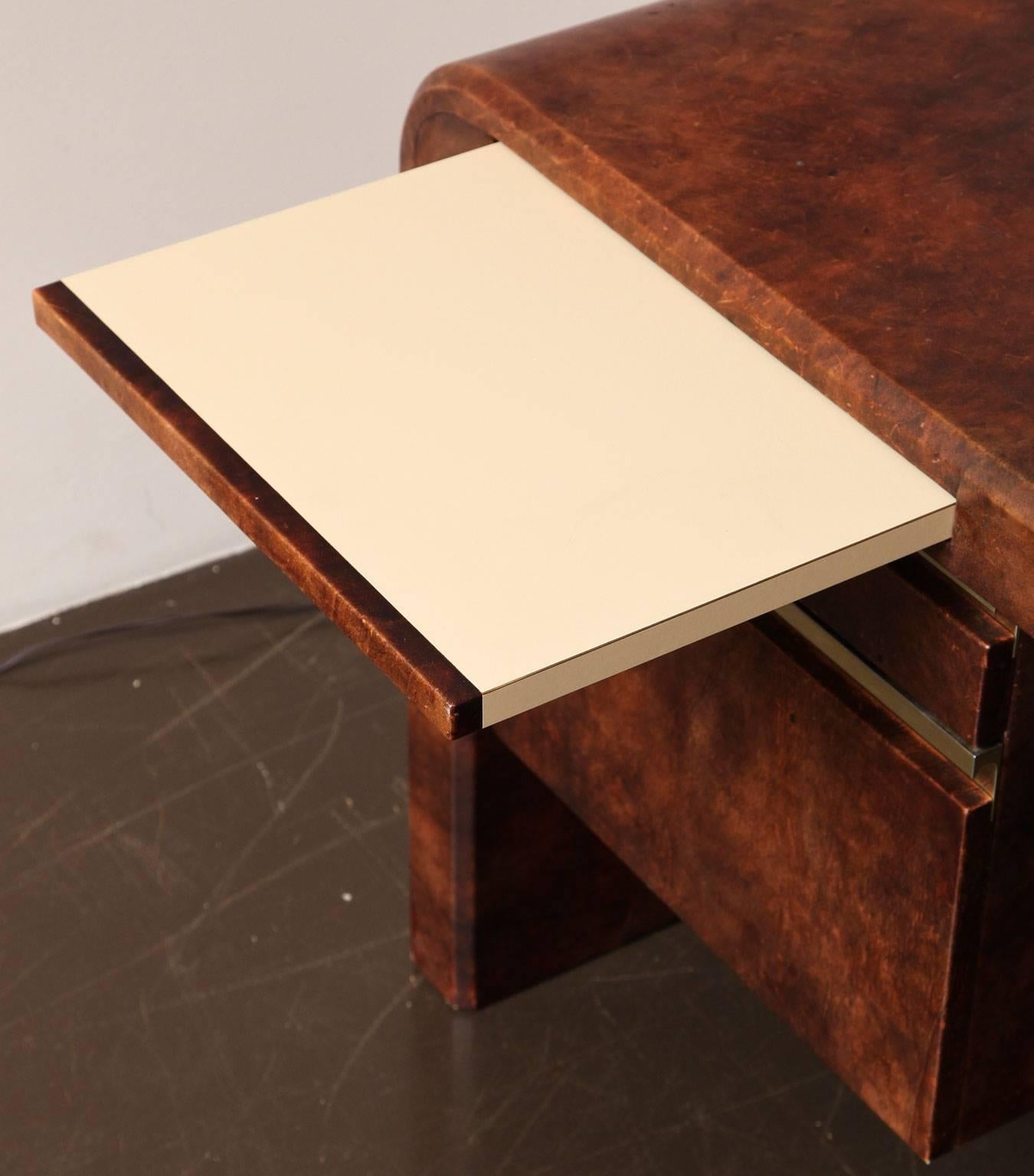 Large waterfall desk by Karl Springer clad in pieced cordovan leather with brass drawer details. Two drawers on each side with a pull-out laminate-topped shelf above,
American, circa 1980.