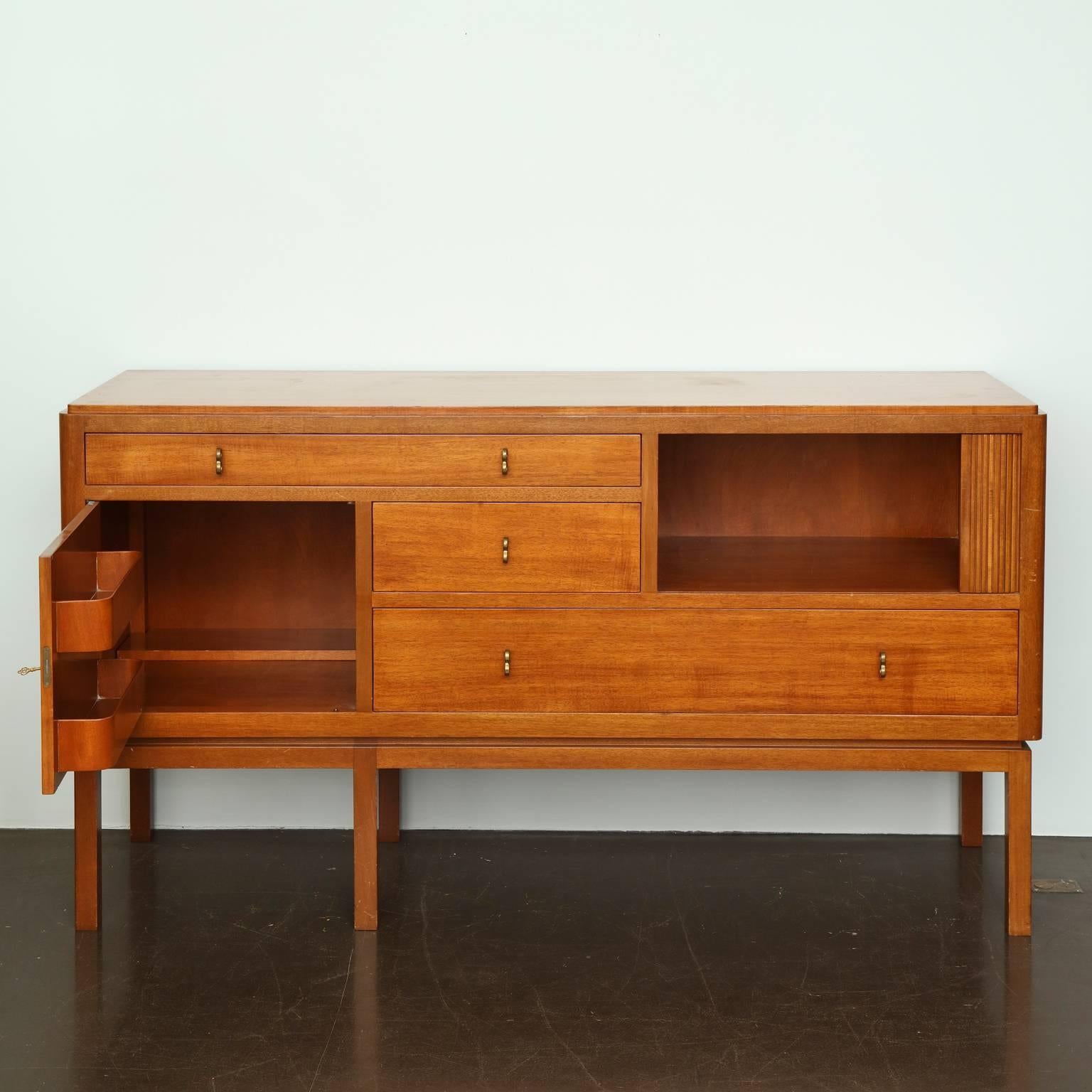 Edward Wormley (1907-1995).
Three-drawer walnut cabinet with one door and tambour front and brass pulls. Raised on six square legs. Signed with Dunbar label.
Executed by Dunbar, American, circa 1950.

This Mid-Century Modern chest would make an