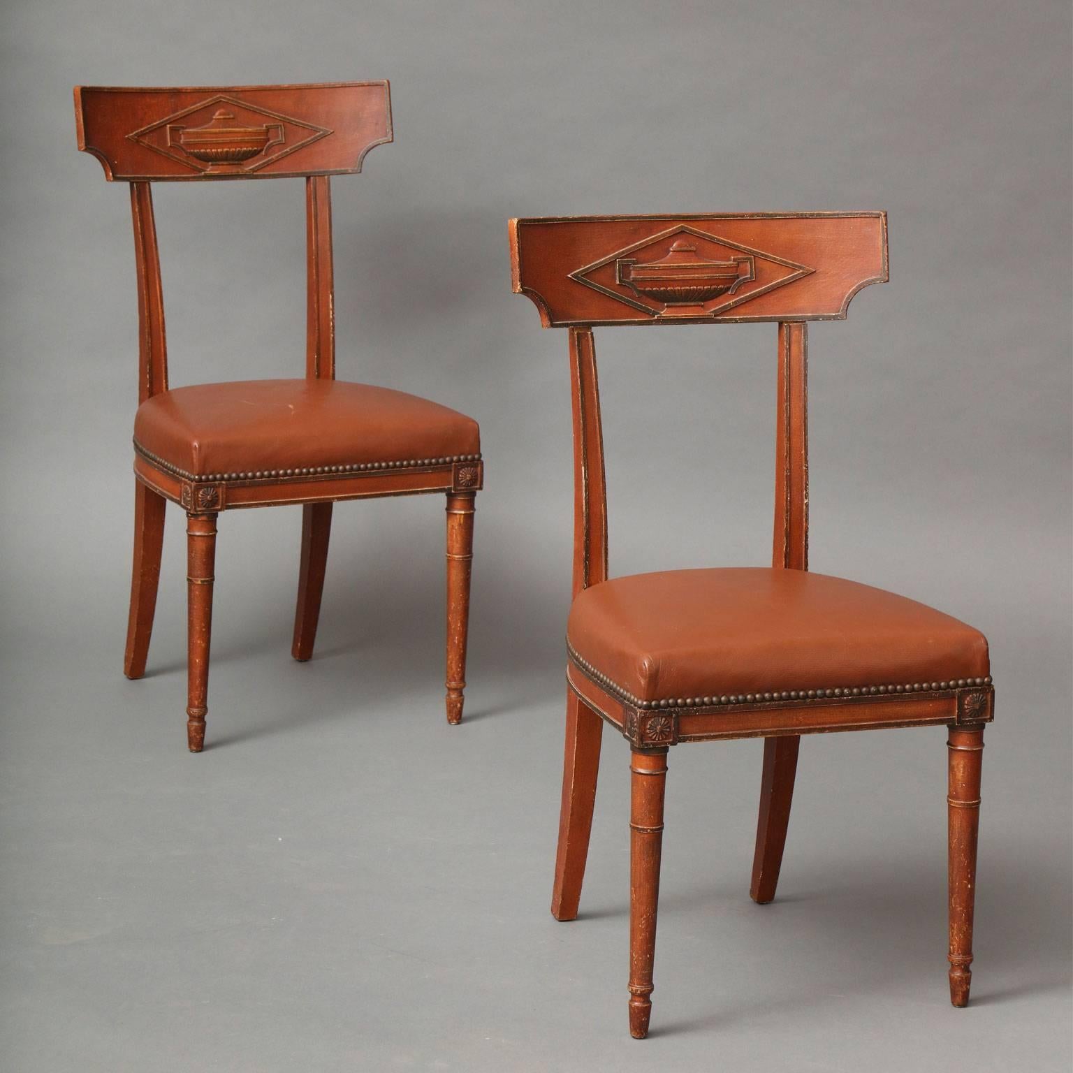 Maison Jansen Pair of Directoire-style side chairs with excellent patina. Classical urn motif carved in back, leather seat with nailhead trim raised on tapering front legs and saber back legs. Painted wood finish in a deep terracotta red with