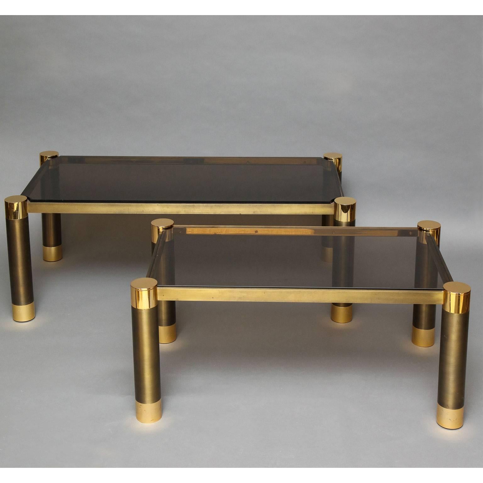 Karl Springer (1931-1991)
Near pair of low tables in brass with smoked glass tops. Brushed antique brass frame raised on column legs with polished brass caps and feet. The smaller table is signed on its short side outside edge. The small table's