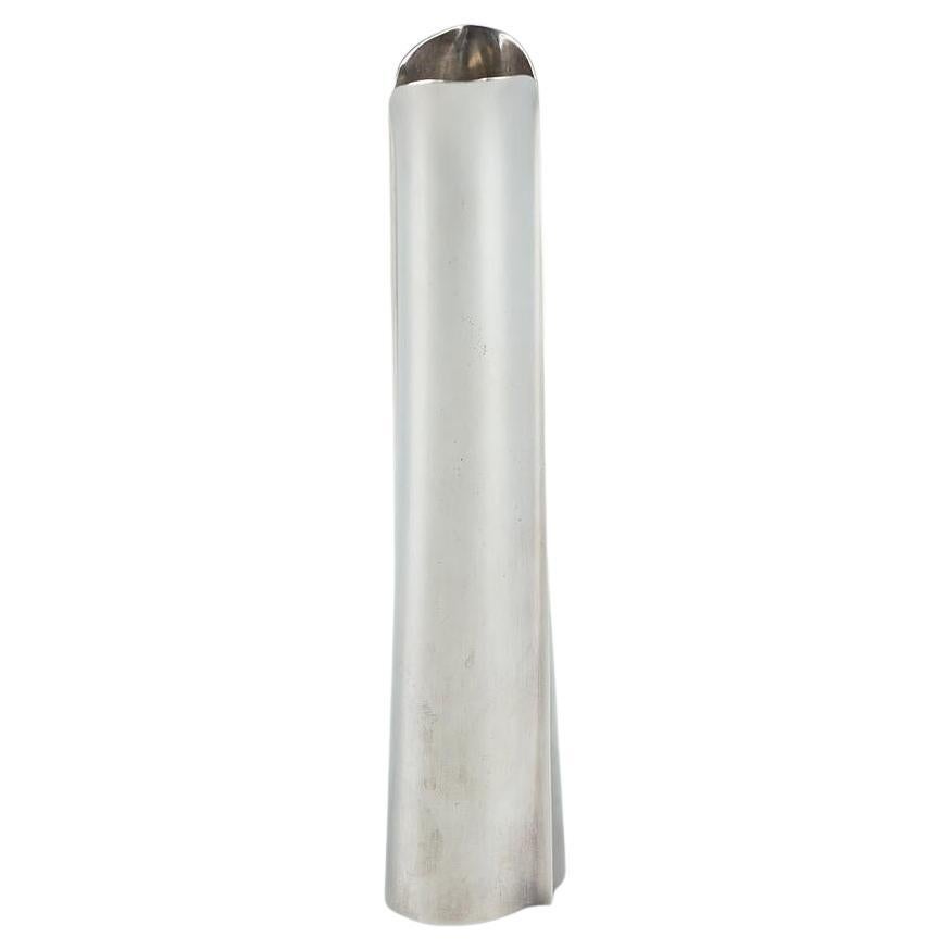 This sterling silver vase, designed in 1954 by Tapio Wirkkala and executed by Kultakeskus Oy in 1959, stands out for its sleek and refined design. The vase features an oval shape with two elegant accolades on either side that taper upwards in a loop
