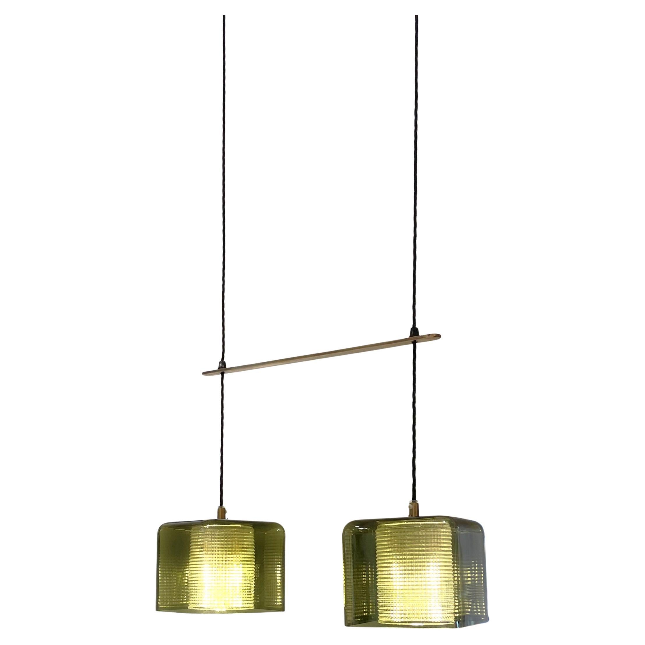 Pendant light by Carl Fagerlund . This glass pendant for Orrefors (Sweden, 1960s)  features two outer cubic shades in green glass, with textured clear crystal cylinders inside that diffuse the light beautifully, creating a soft and warm glow. A