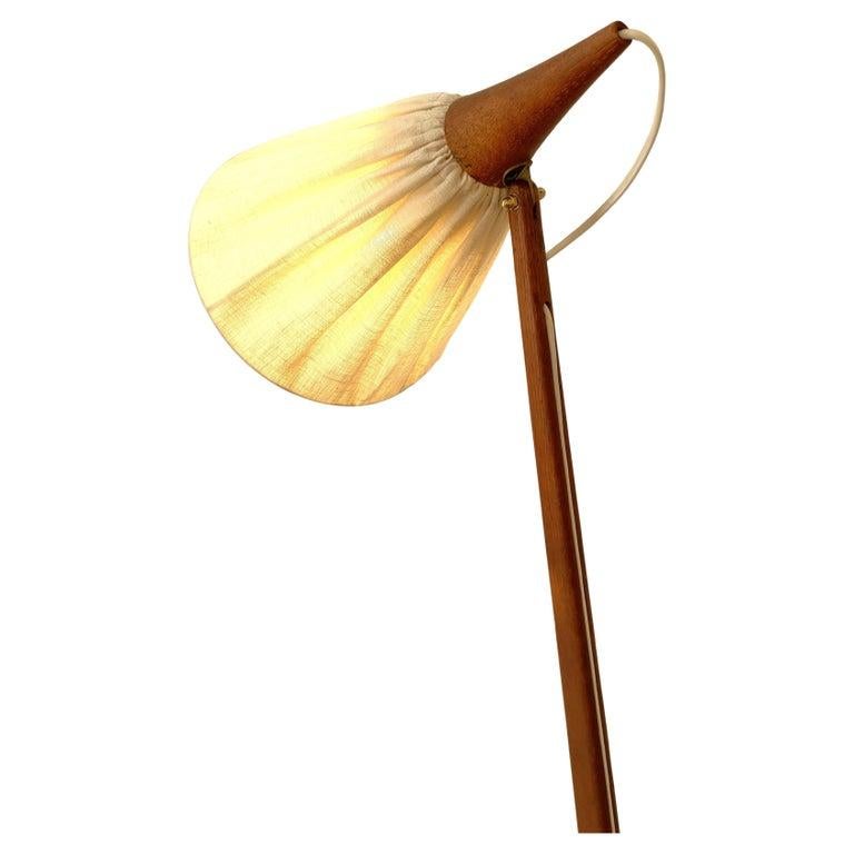 A brilliant design, with a clear aesthetic by Uno & Östen Kristiansson for Luxus. This floor lamp has an oak structure supporting a pleated fabric shade that provides a soft glow in addition to directional light. The white electrical cord, well
