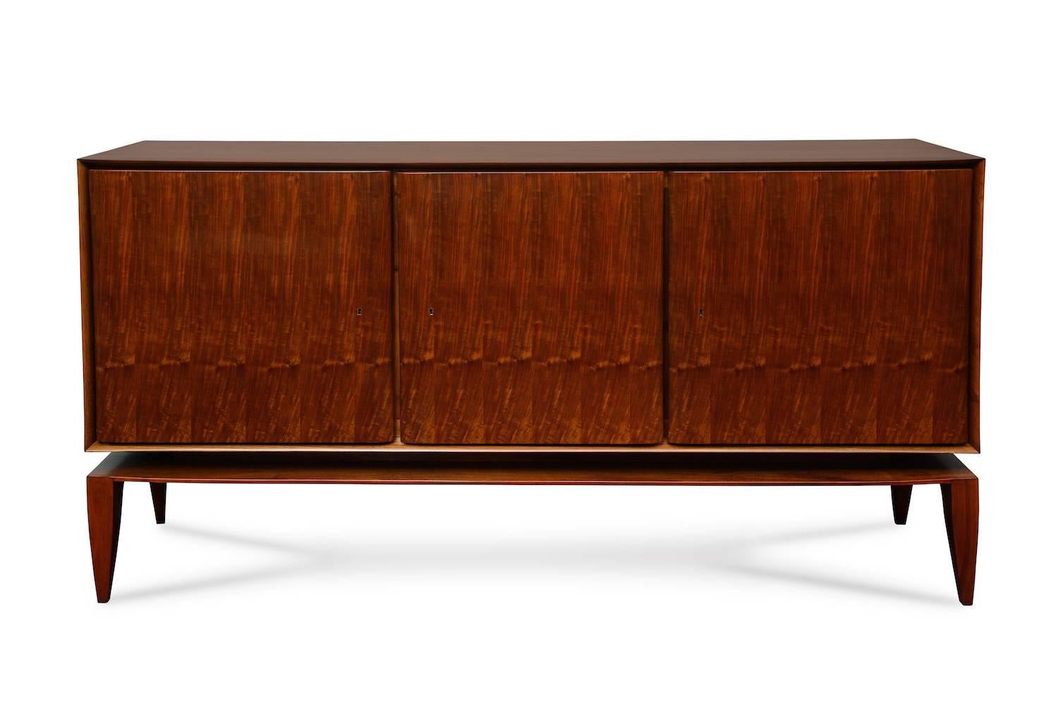 Rare Three-Door Floating Cabinet by Gio Ponti for M. Singer & Sons. Mahogany cabinet raised on tapering legs. Three knife-edge doors, set into a beveled frame so the doors appear to float. Interior drawers and open shelves. This cabinet was