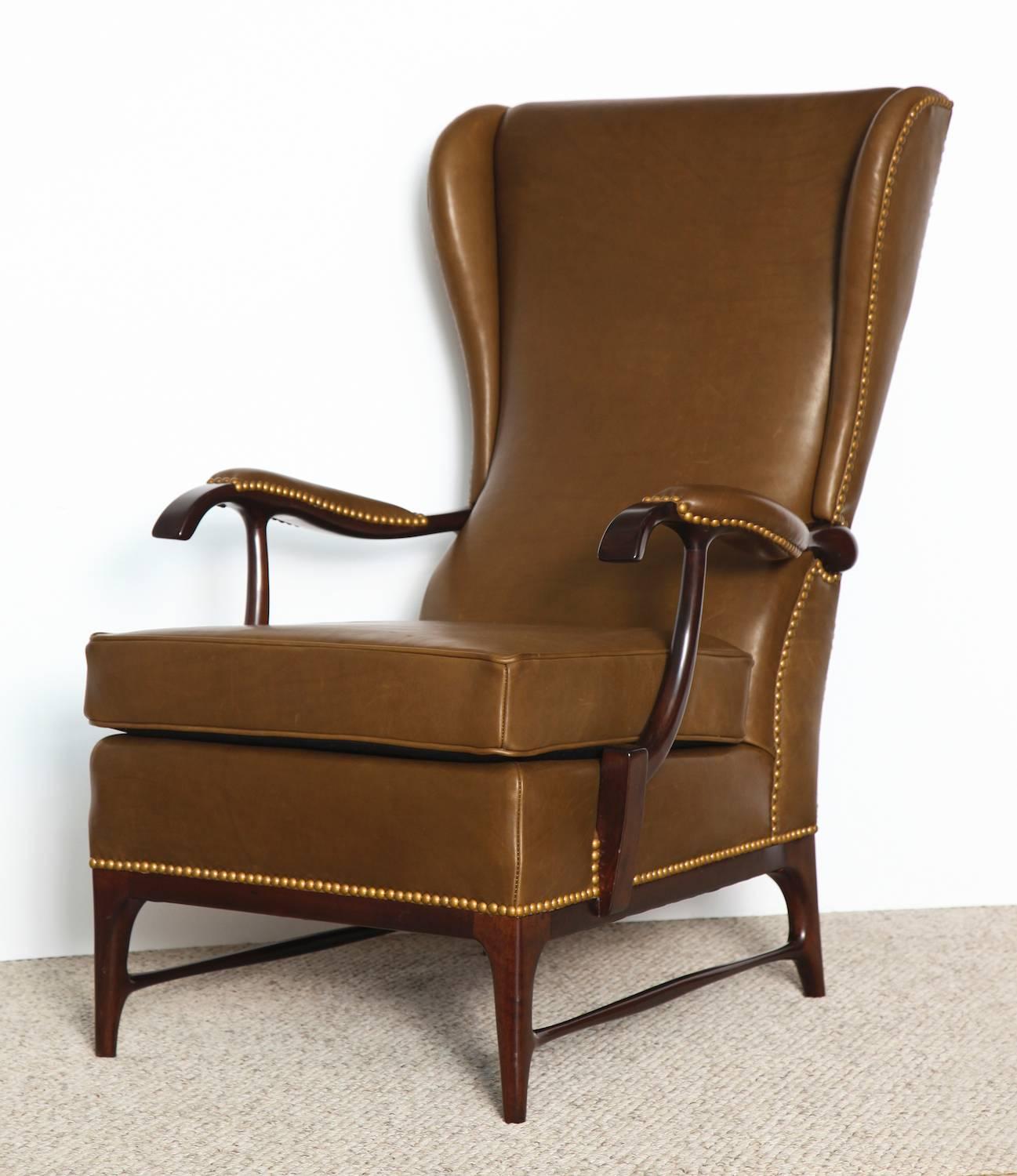 Pair of high back lounge chairs by Paolo Buffa.  Beautiful darkwood frames, newly upholstered in brown leather with nailhead trim. Great sculptural forms and intricate detailing.
