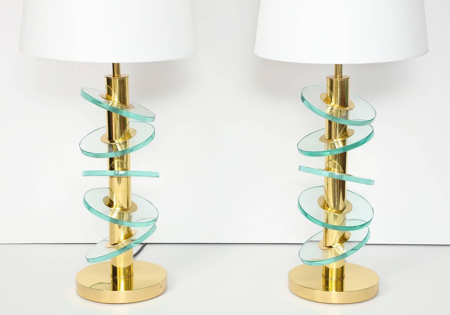 Studio-made table lamps by Fedele Papagni. Segmented brass columns engineered to connect with angled glass discs. Meticulous construction imbued with a playful spirit. Each lamp has two candelabra sockets concealed by paper shades. Made to order,