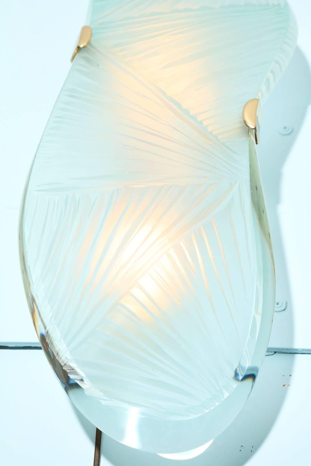 Studio-made “Ares,” sconces by Ghiró Studio. Large-scale sconces featuring thick, curved glass slabs with deeply carved fronts and curved, beveled edges. Custom-made brass structures with arm supports to hold glass panels. Two standard sized Edison