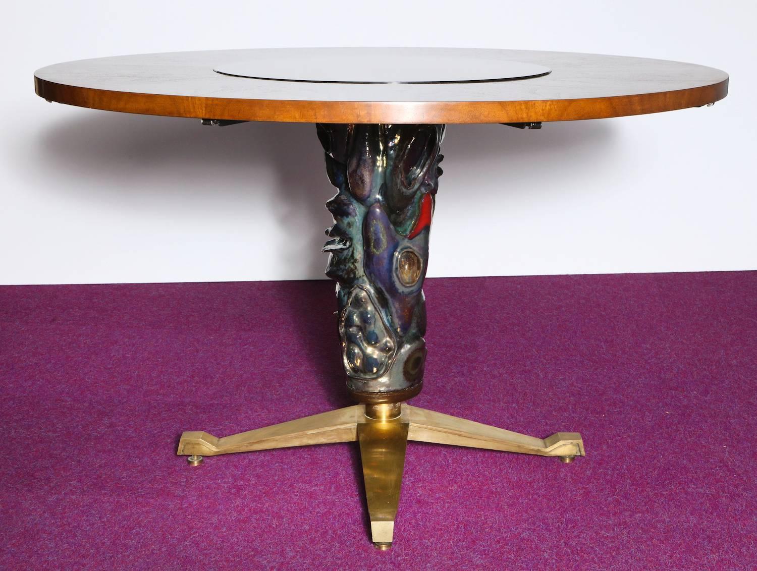 Circular center or dining table by Melchiorre Bega for Altamira. Rare and extraordinary table featuring a pedestal base with a large ceramic sculpture by Pietro Melandri and inset glass panel with reverse-gold-relief by Angelo Bragalini. Walnut top