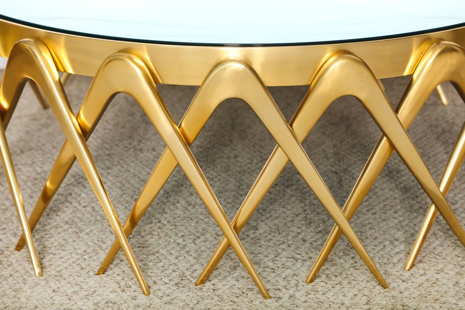“Compasso,” circular cocktail table by Roberto Giulio Rida. Solid brass legs inspired by the lines of a compass and repeated around the perimeter of base. Clear glass top over colored glass lens.  Acquired directly from the artist and sold