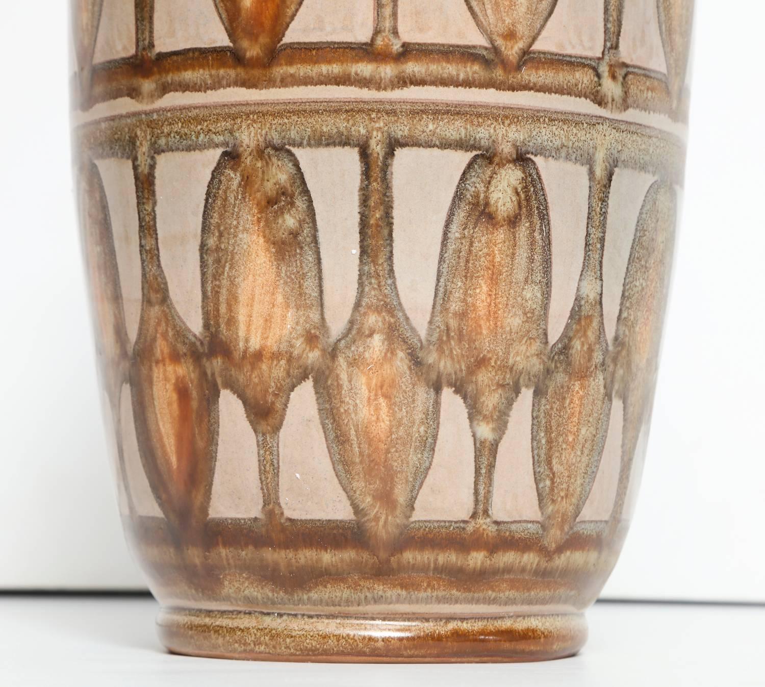 Slender vase with pinched neck and repeated pattern. Glazes in cream, rust and browns. Signed and dated on underside.