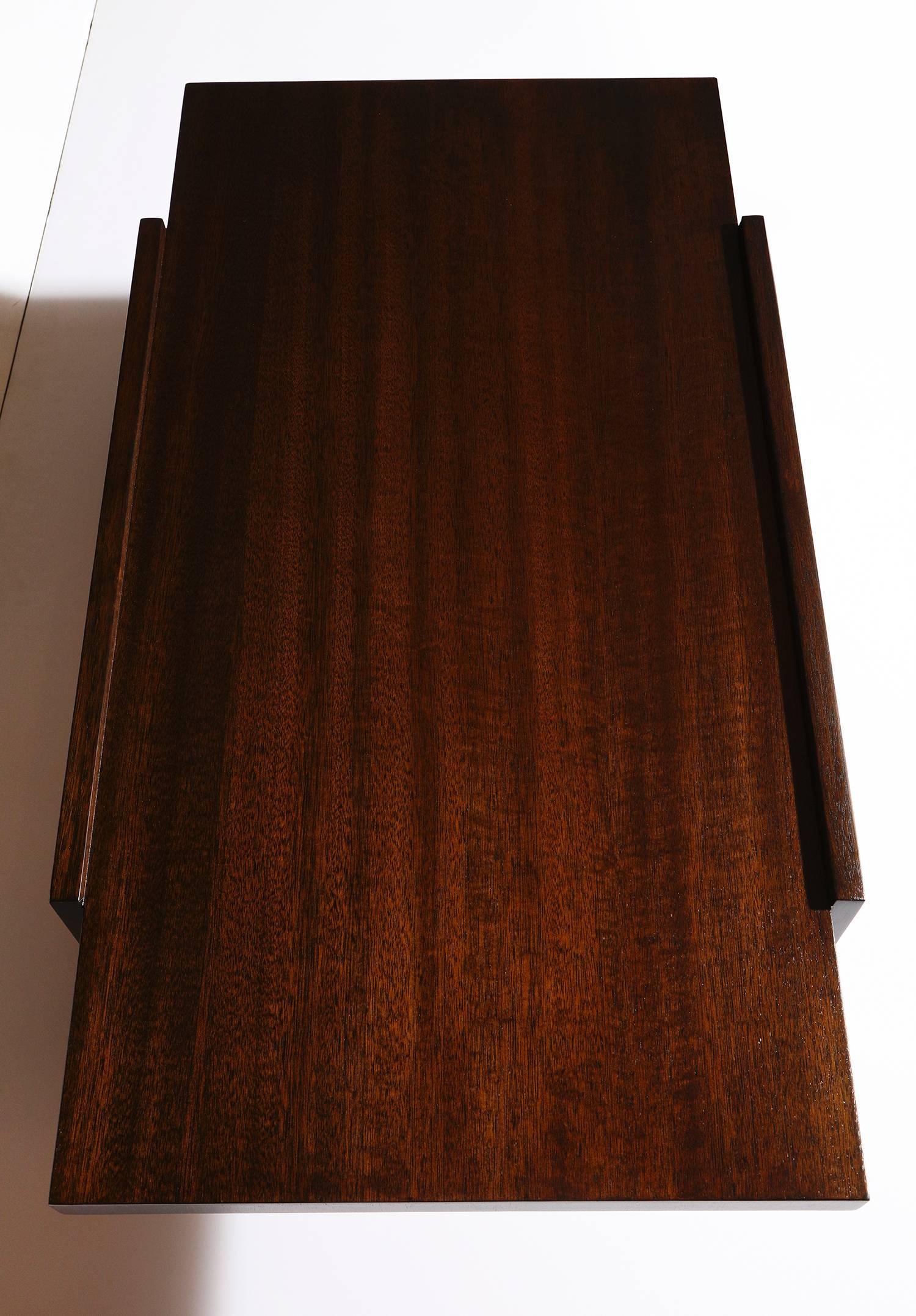 Architectural cocktail table by Paul Laszlo for Brown Saltman. Dark stained mahogany top floating on two rectangular side supports. Recently refinished and signed on underside.