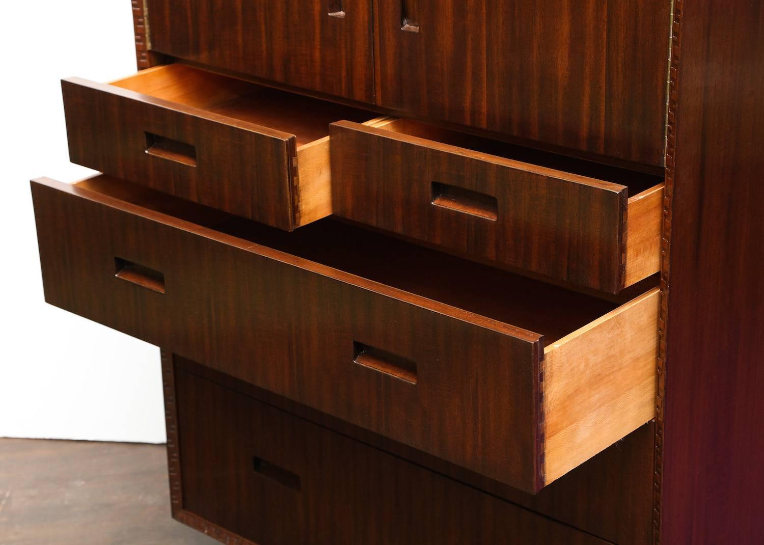 Frank Lloyd Wright for Heritage Henredon, model #2000.  Six-drawer chest of dark stained mahogany with carved detailing and an architectural base. Two doors open to reveal three slotted storage areas, and all drawers and doors have clean inset