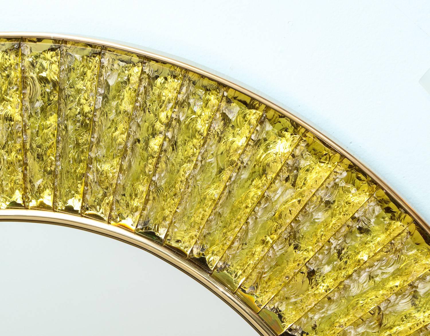 Studio-built circular mirror by Ghiró Studio. Hand-cut and chiseled slabs of yellow-colored crystal surround a central, circular mirror. Brass surround and mount. Signed on outer edge.