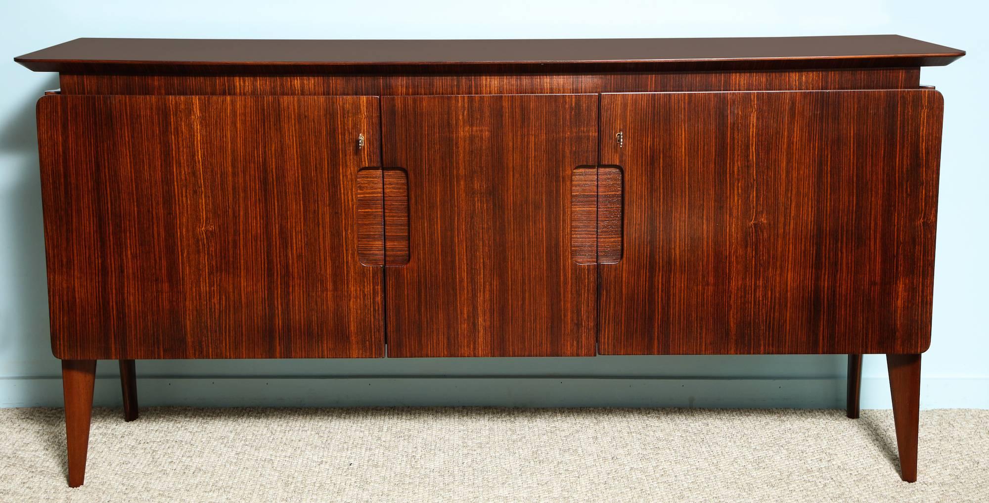 Rare two-door sideboard by Ico Parisi. Cabinet of Indian rosewood with inset panels that act as door pulls. Raised door panels, beveled edges, and shaped legs. Both doors open to reveal storage with interior shelf. Manufactured by Rizzi, Cantu,
