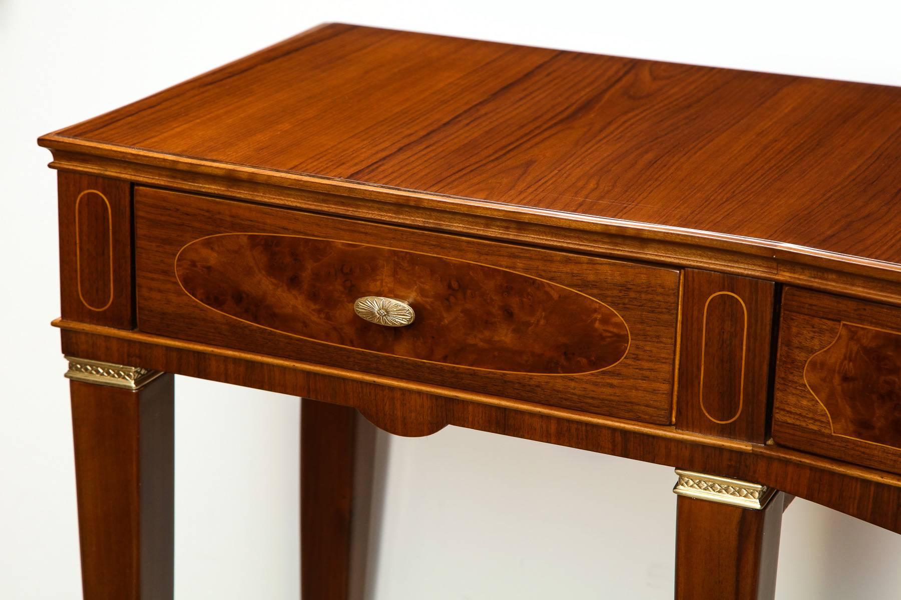Paolo Buff three-drawer console table. Extraordinary table of teak, mahogany and burled wood with light wood inlays. Bowed center front section, three drawers with cast brass pulls and brass mounts on legs. An excellent example of the cabinet making