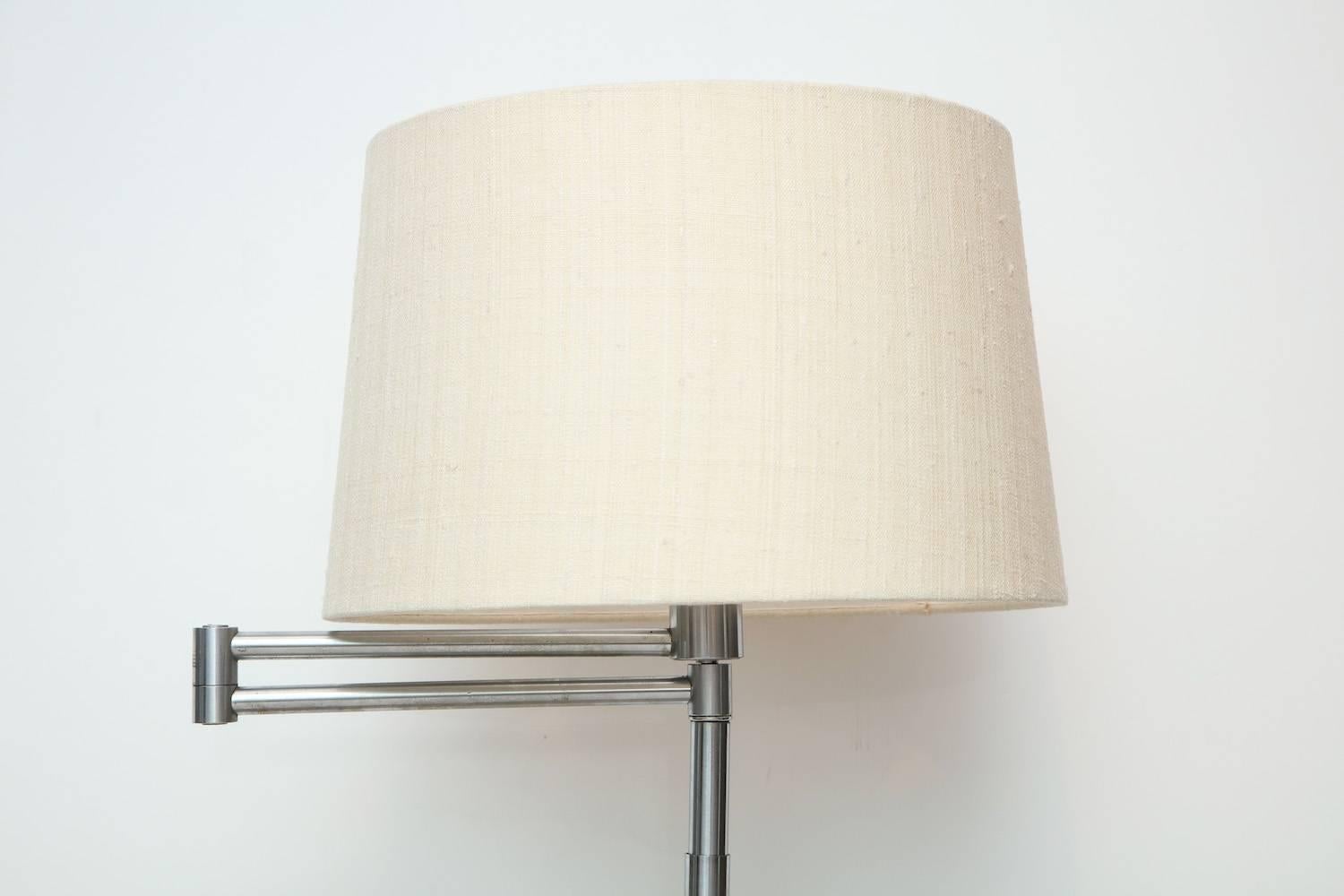 Early swing arm floor lamp by Nessen Studio. Oxidized chrome lamp with swing-arm feature and original bakelite turn switch. Recently polished out, with new sockets, wiring and linen shade. A fantastic early example of an iconic design. Signed on