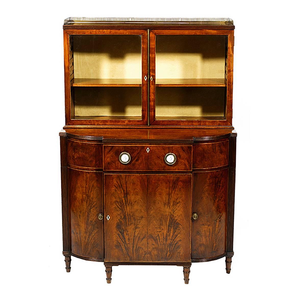 Early 19th century mahogany breakfront display cabinet. The moulded top section with a brass gallery rail above two glazed doors. The bottom section with moulded top on a single curved long drawer with boxwood stringing enclosing eight finely made