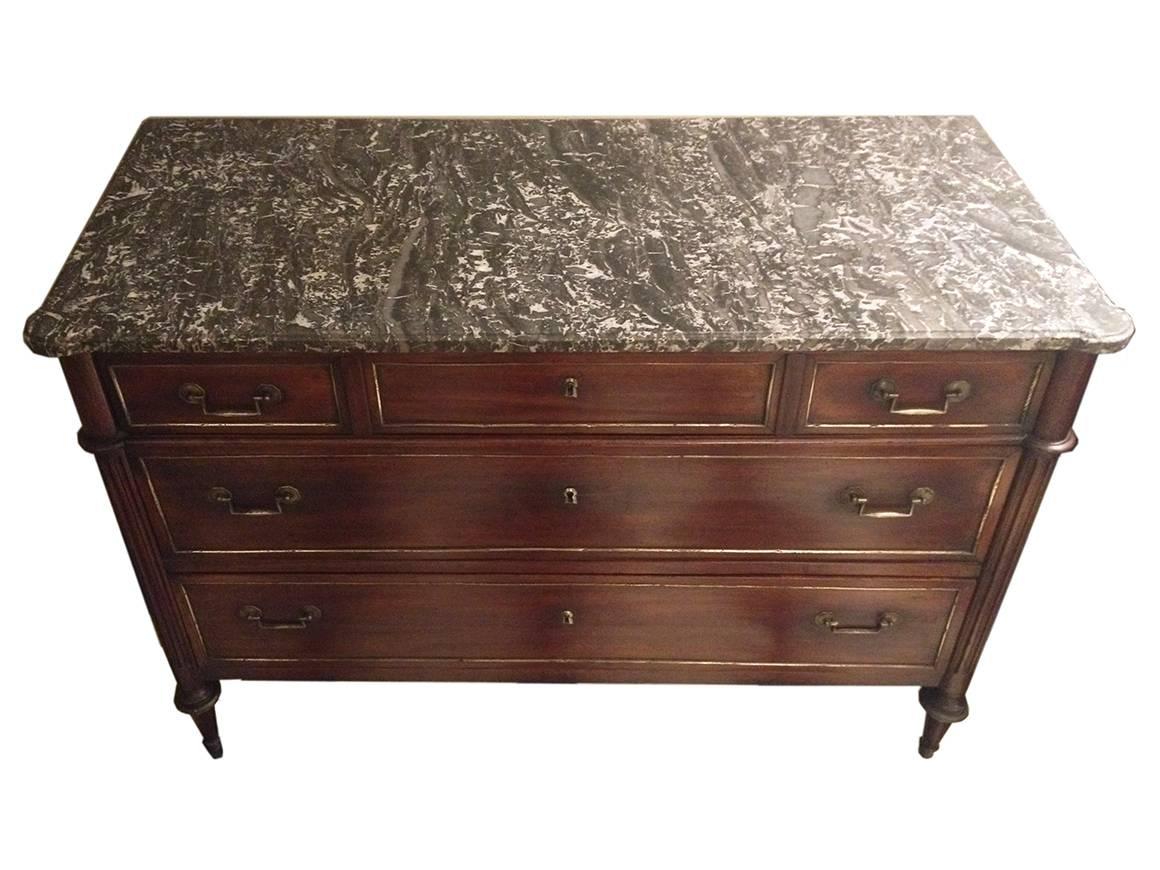 Early 19th century Charles X marble-top mahogany commode. Cove-edged marble atop a neoclassical case with fluted columns over brass-capped conical legs. Three long drawers with brass trim and bail-pull handles.