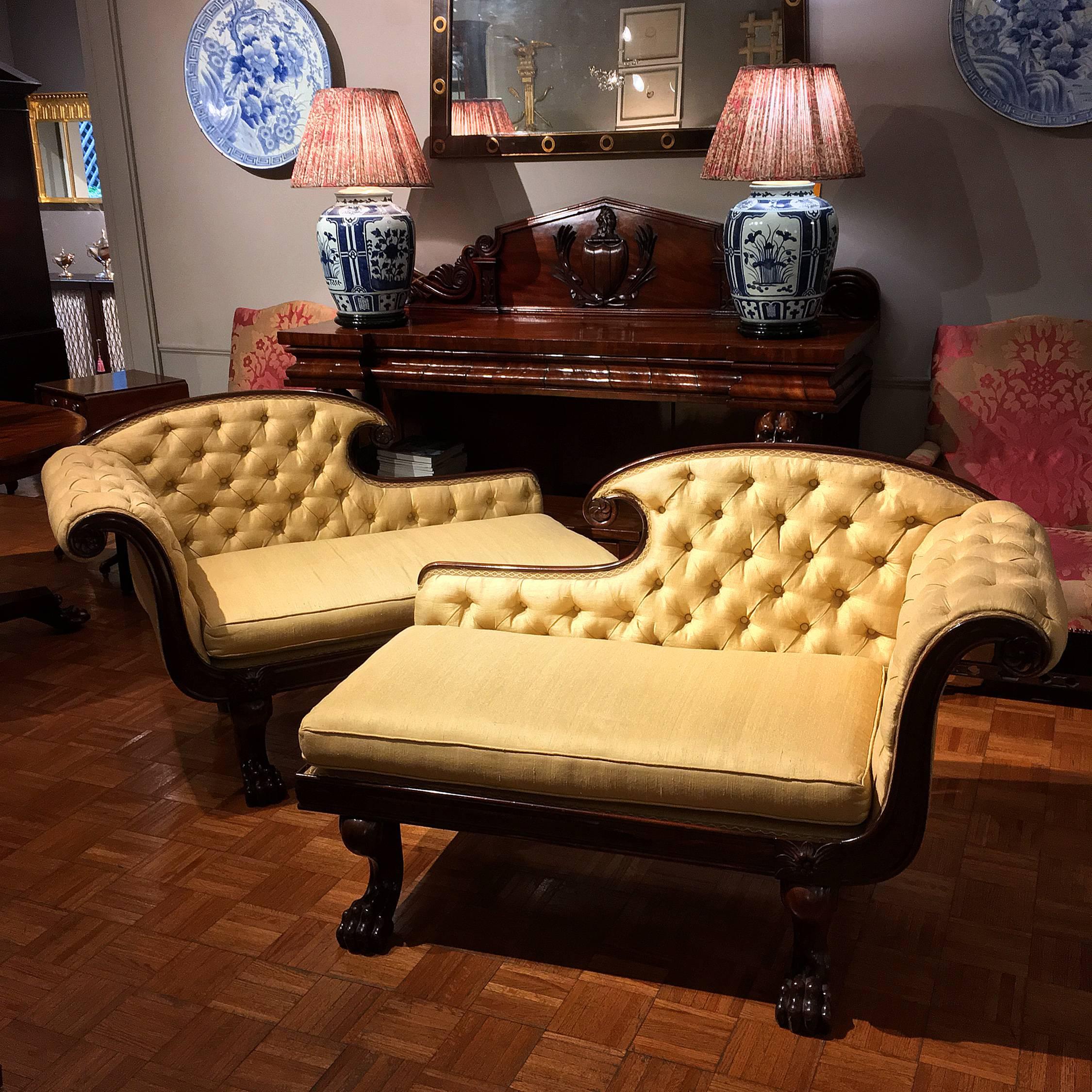 This pair of early 19th-century William IV chaises longues or chaise lounges is distinguished by their unusually small size. They are ornamented with carved rosettes, and with lion's paw feet in the front and turned legs in the back. Each with