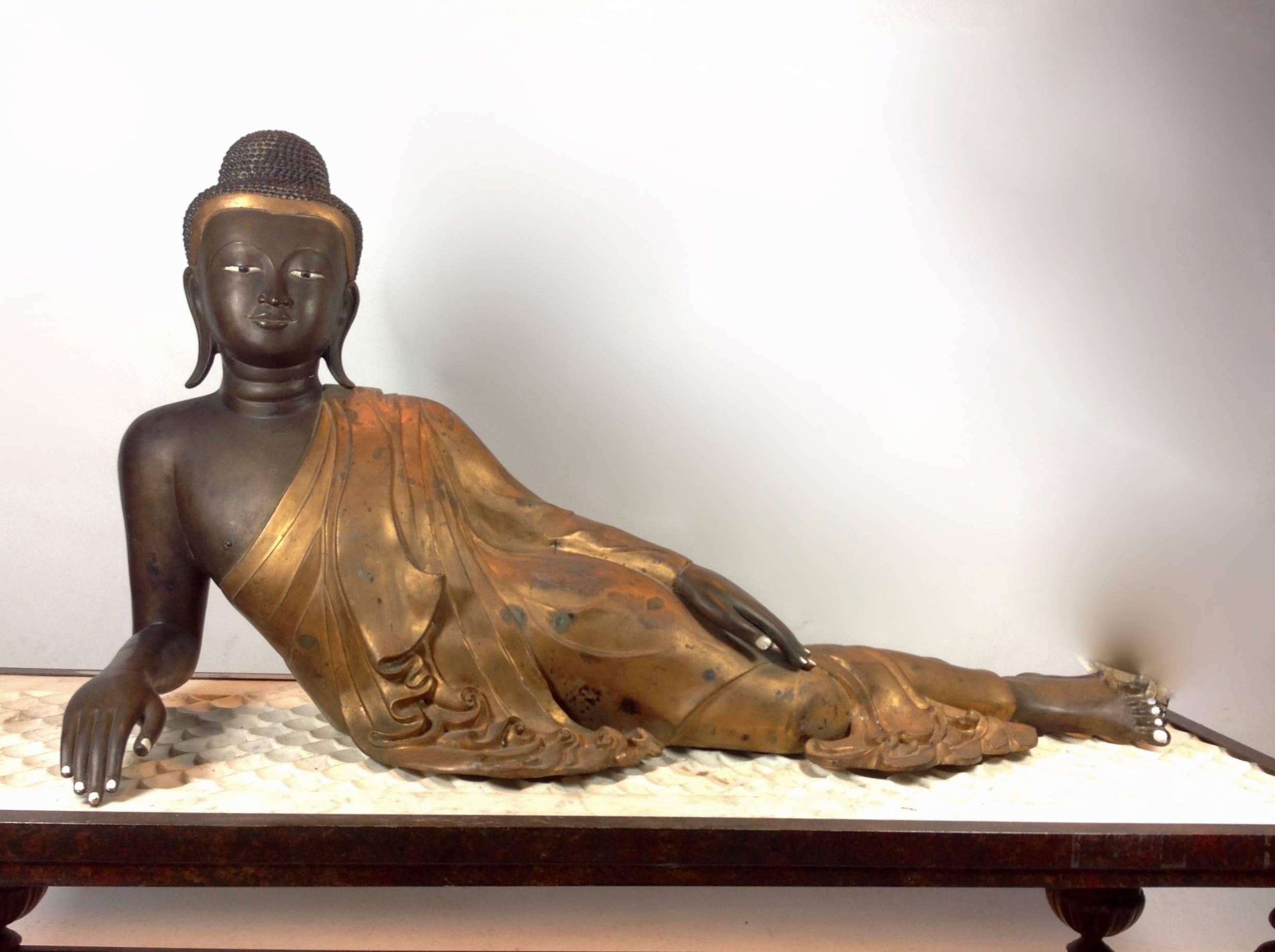 A gorgeous lifesize reclining Buddha; Burmese; circa 1800s. Exquisite countenance and robe detailing in cast bronze.