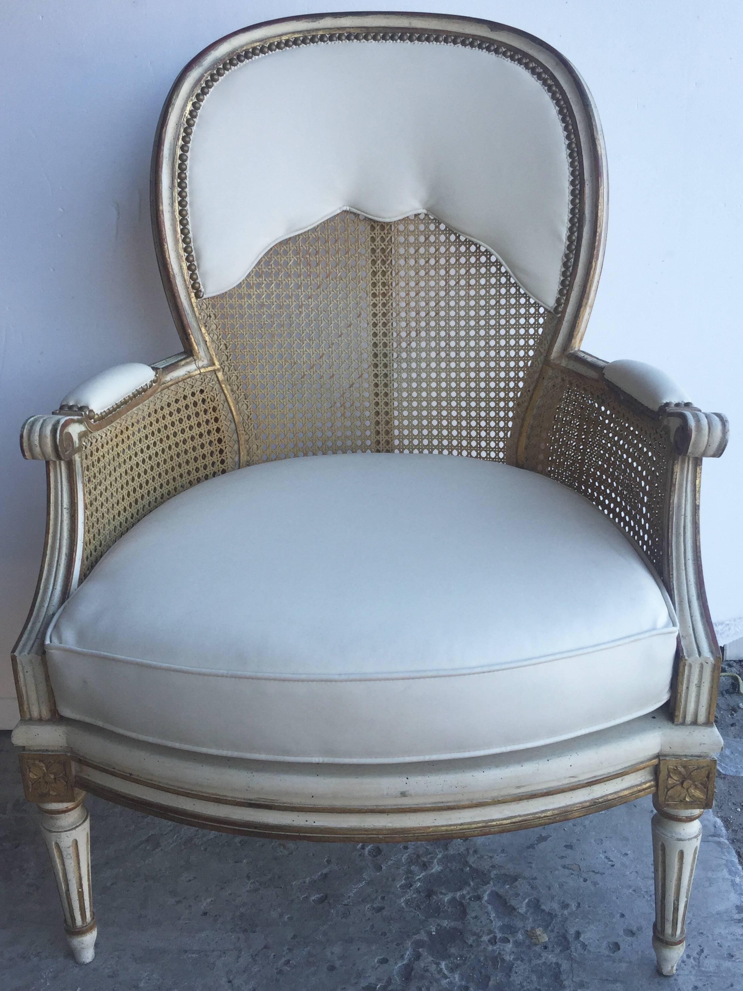 Beautiful pair of Italian painted and gilded bergères, circa 1940. Grand scale and elegant design. Beautiful combination of natural wicker and distressed painted finish makes the chair timeless and chic.. Reupholstered circa 1970s.