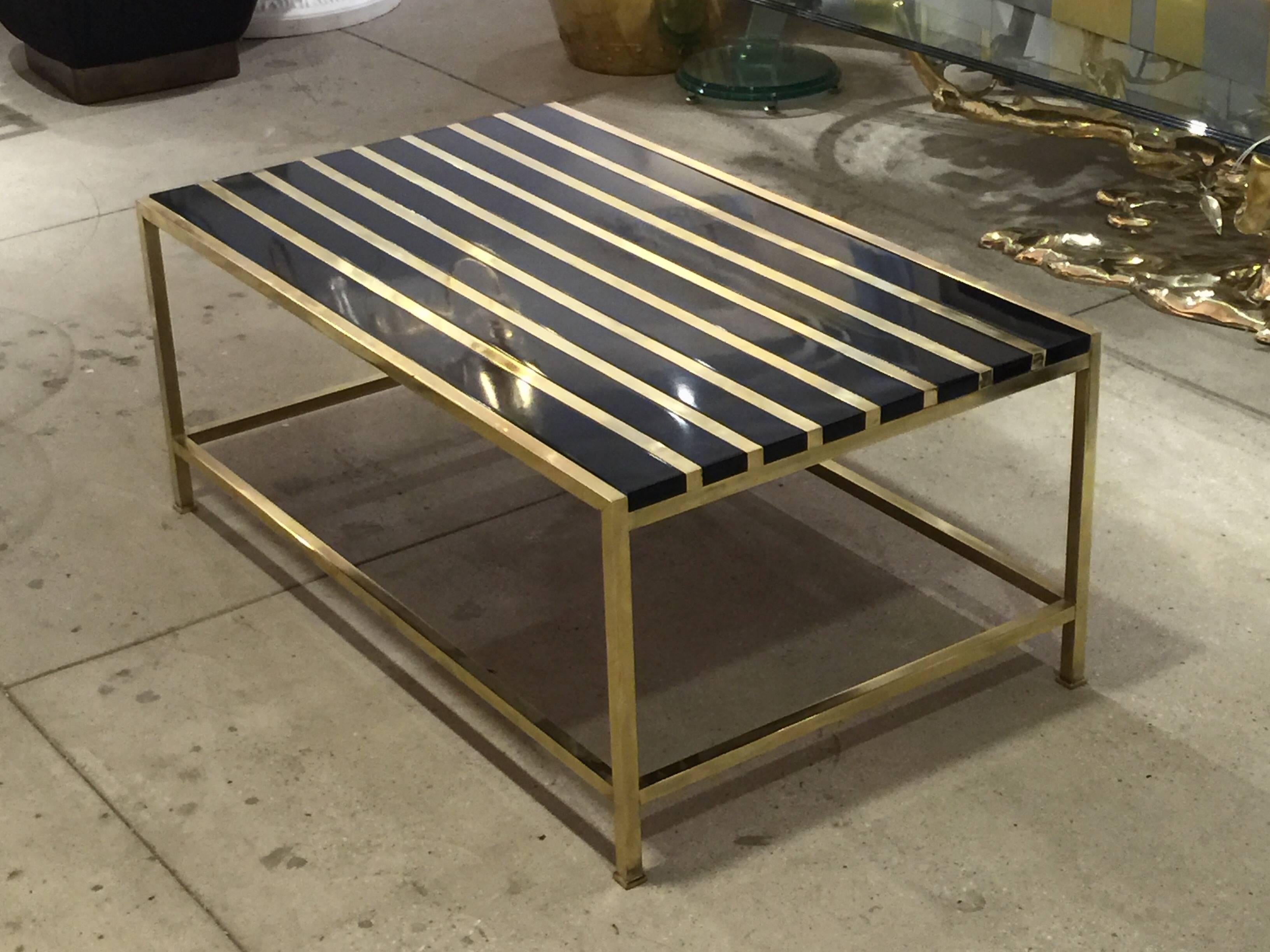 Brass and lacquered wood coffee table.
This table has a custom crafted top which floats atop this Mid-Century brass base.
Simple clean lines with an elegant chic twist. Base is vintage, 
circa 1960s.
