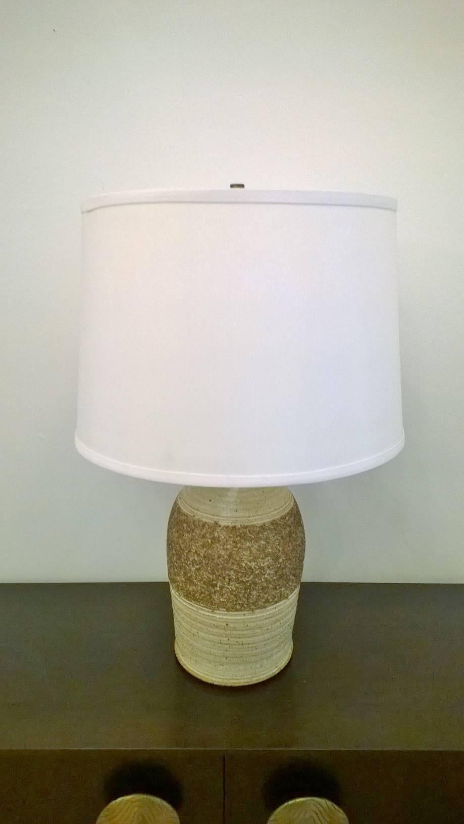 An original pair of 1960s American art pottery table lamps in earth tone colors of cream and brown. They have aged brass fittings. The ceramic bodies are handmade and differ slightly with their top necks. They are the same size and color. Newly