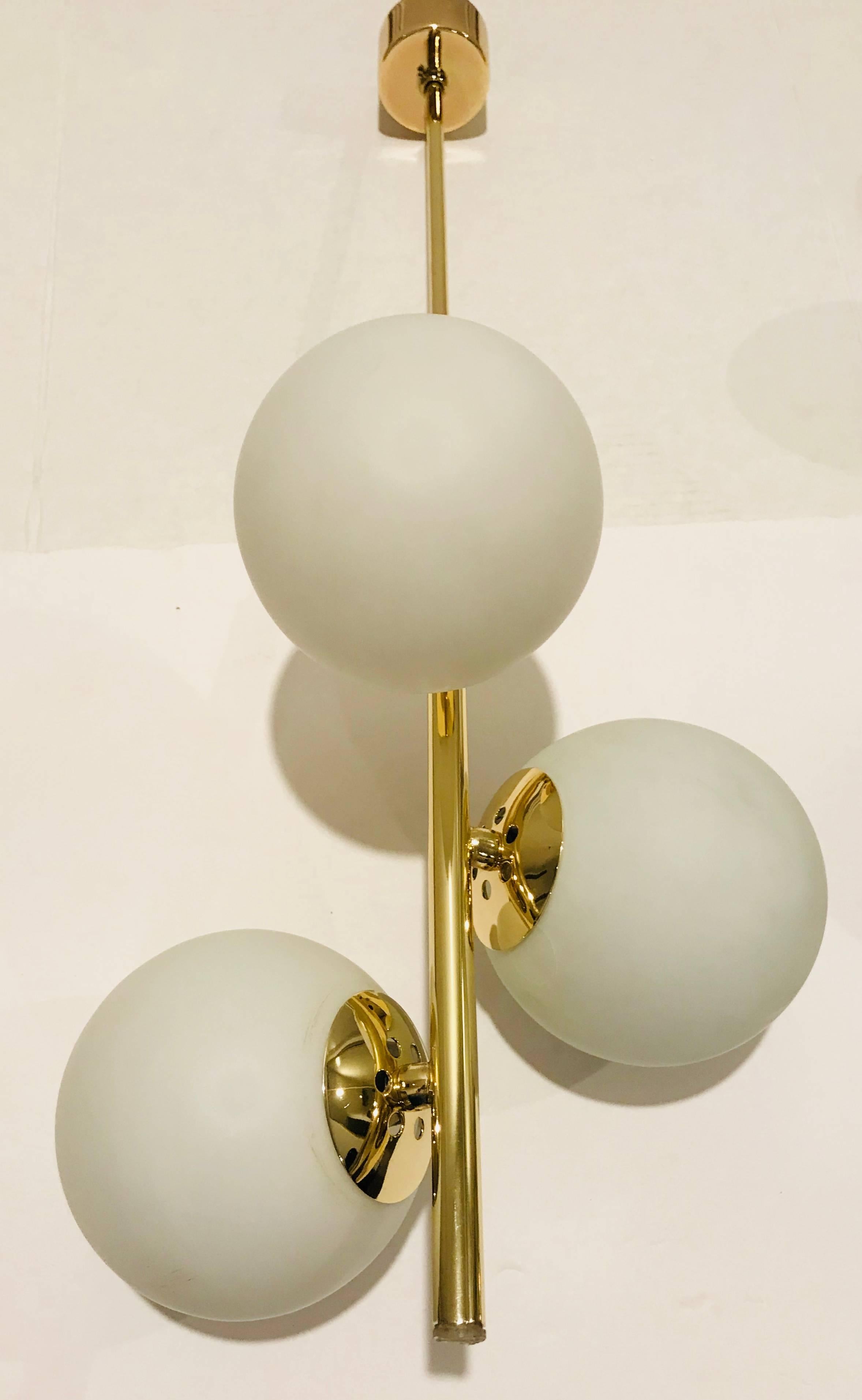 A wonderful pair of 1950s Italian polished brass and white globe pendant lights. Newly rewired. The ceiling pole can be shortened or lengthened depending on need.