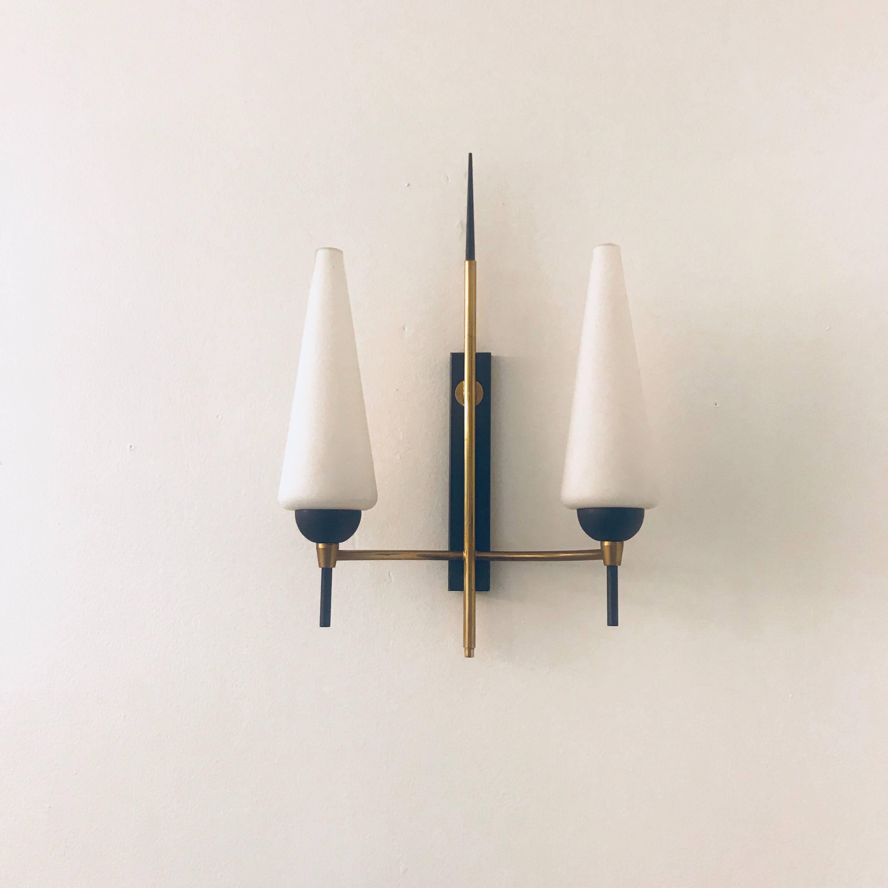 A set of two 1960s French wall lights composed of golden brass and black enamel frames holding white cone glass shades. Newly rewired with matching backplates. 120 Watts each . The sconces are by the French lighting company, Lunel.