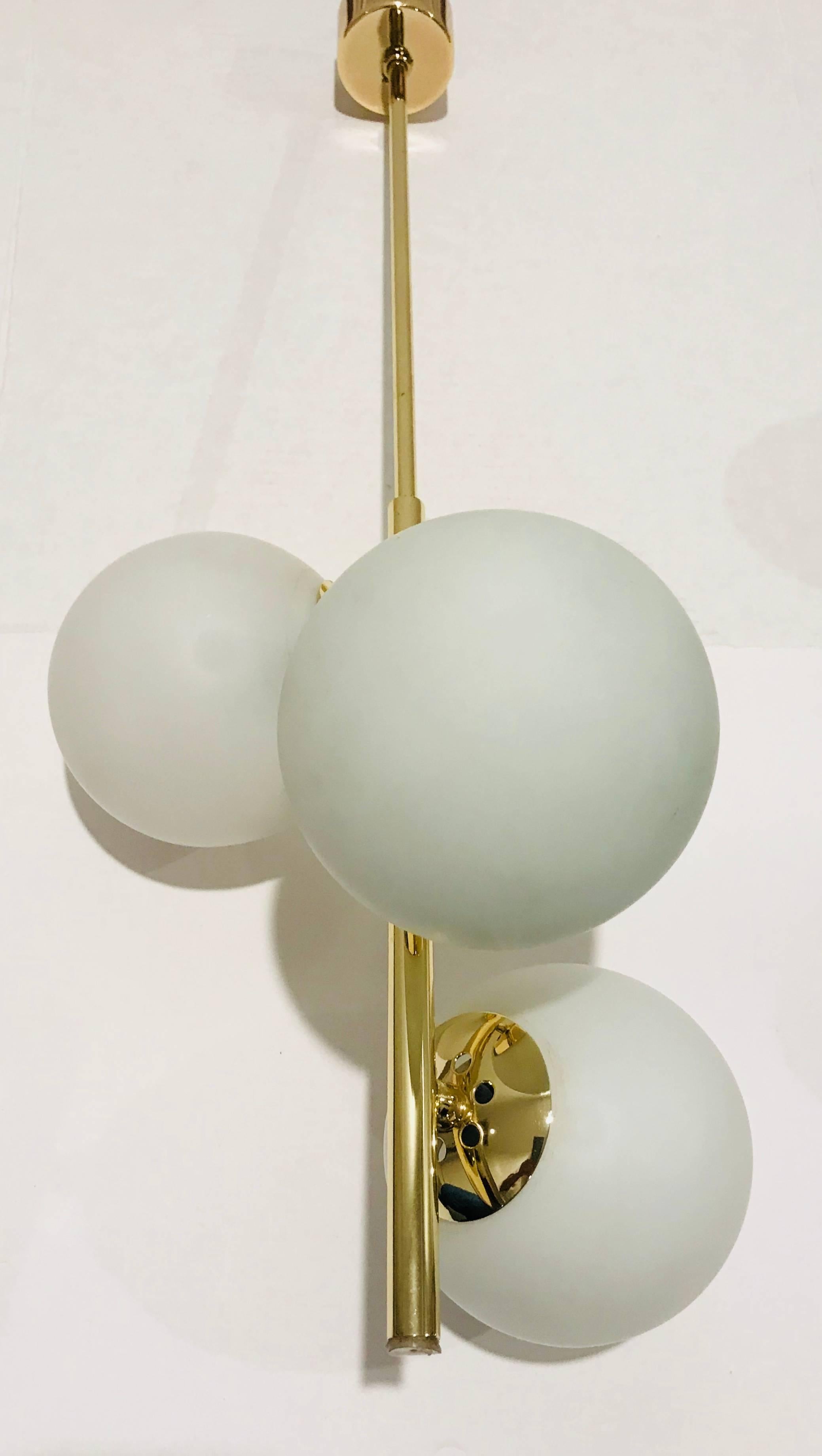 A golden polished brass 1950s Italian pendant with three white glass globe shades. Newly Rewired.