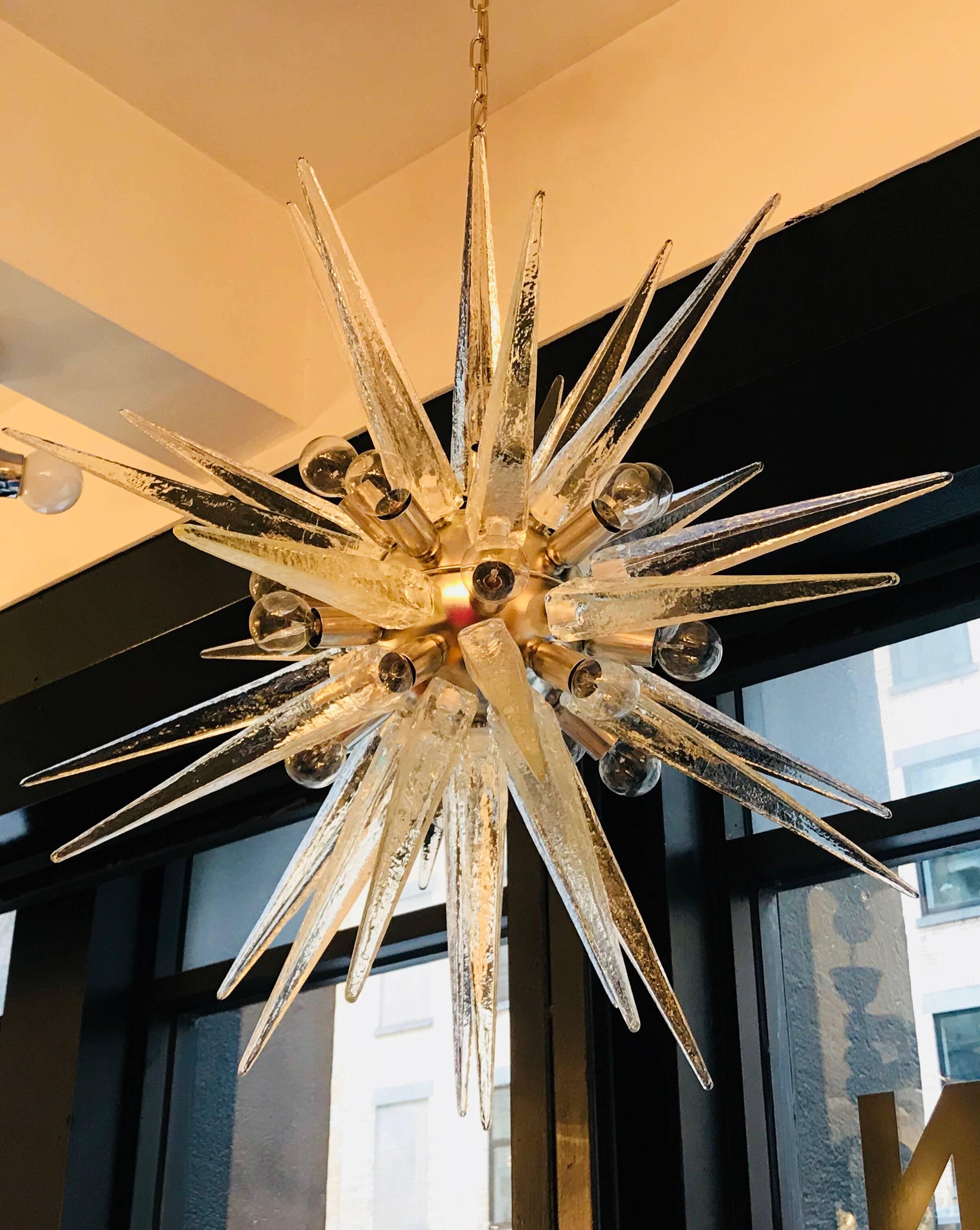A luxurious, , 1970s snowflake Sputnik light composed of a polished chrome sphere body and thick solid Murano glass obelisk shaped elements . The textured glass resembled ice. Twenty light sources. Newly Rewired. The glass body at it’s widest is 33”