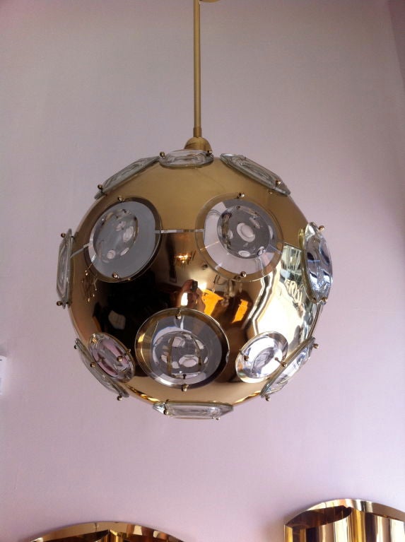 A polished brass sphere light with reflective glass prism eyelets. Five-light sources.