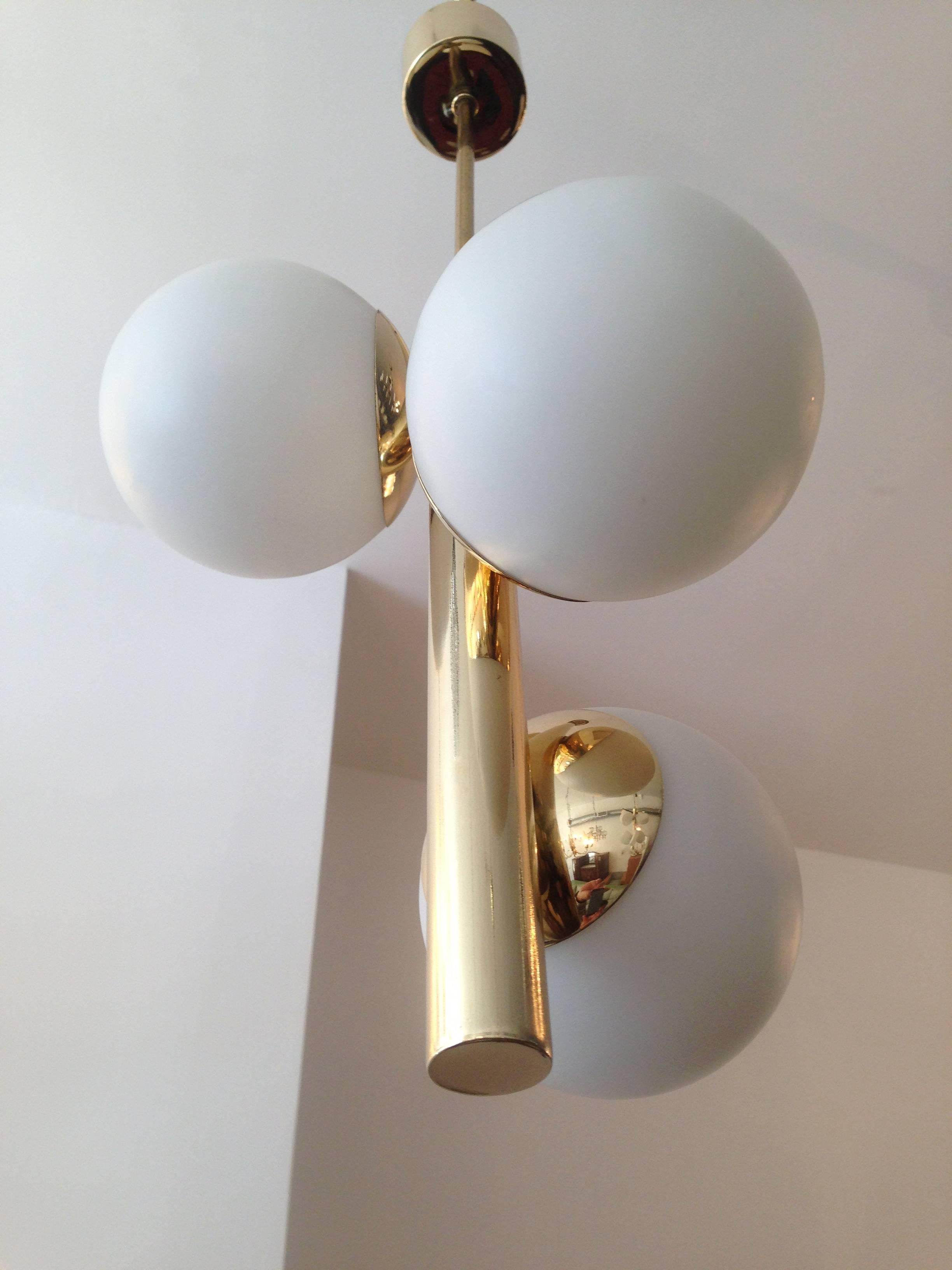 A great set of three Italian pendants composed of polished brass fixtures and matte white glass ball shades. Rewired.