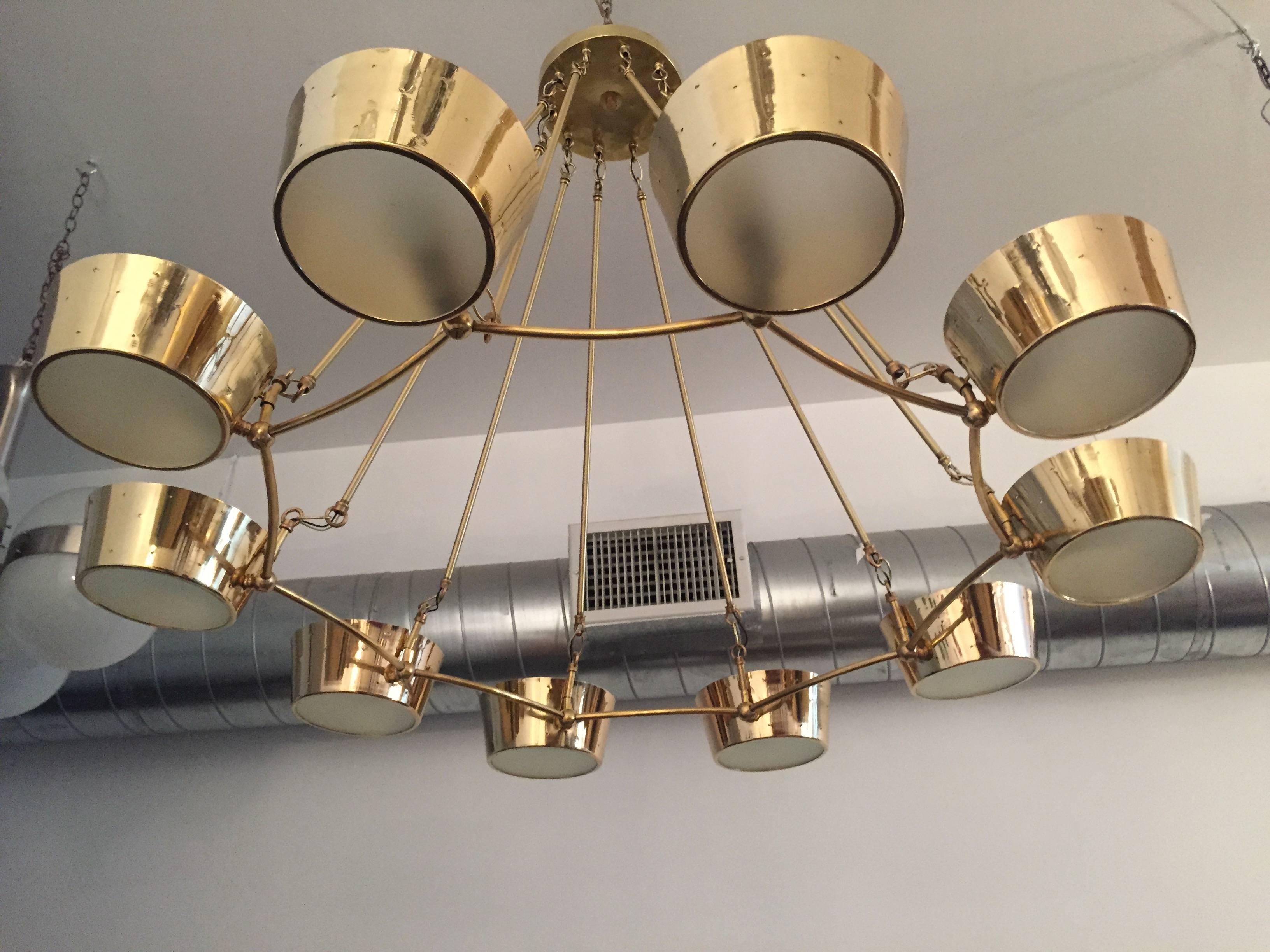 A wonderful American, 1950s Mid-Century Modern chandelier by famed lighting company, Lightolier. The large chandelier is composed of a polished brass body with perforated holes that emit light and frosted glass shades. Ten light sources up to 800