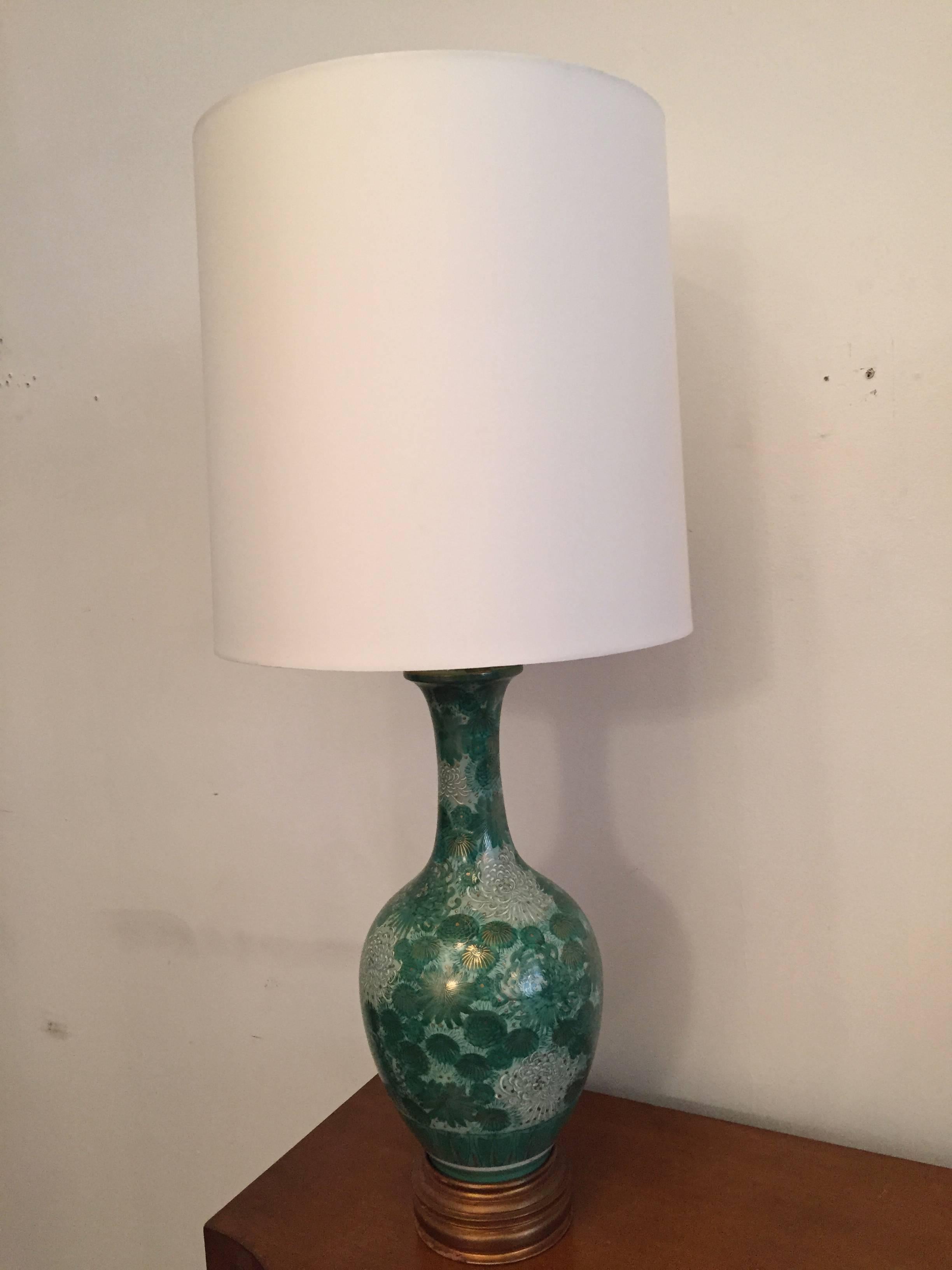A rich, elegant pair of 1950s American table lamps composed of hand-painted Japanese Moriage vases with giltwood bases. The ceramic bodies are composed hand-painted in a floral pattern colors of green and white. Newly rewired. Original label.
