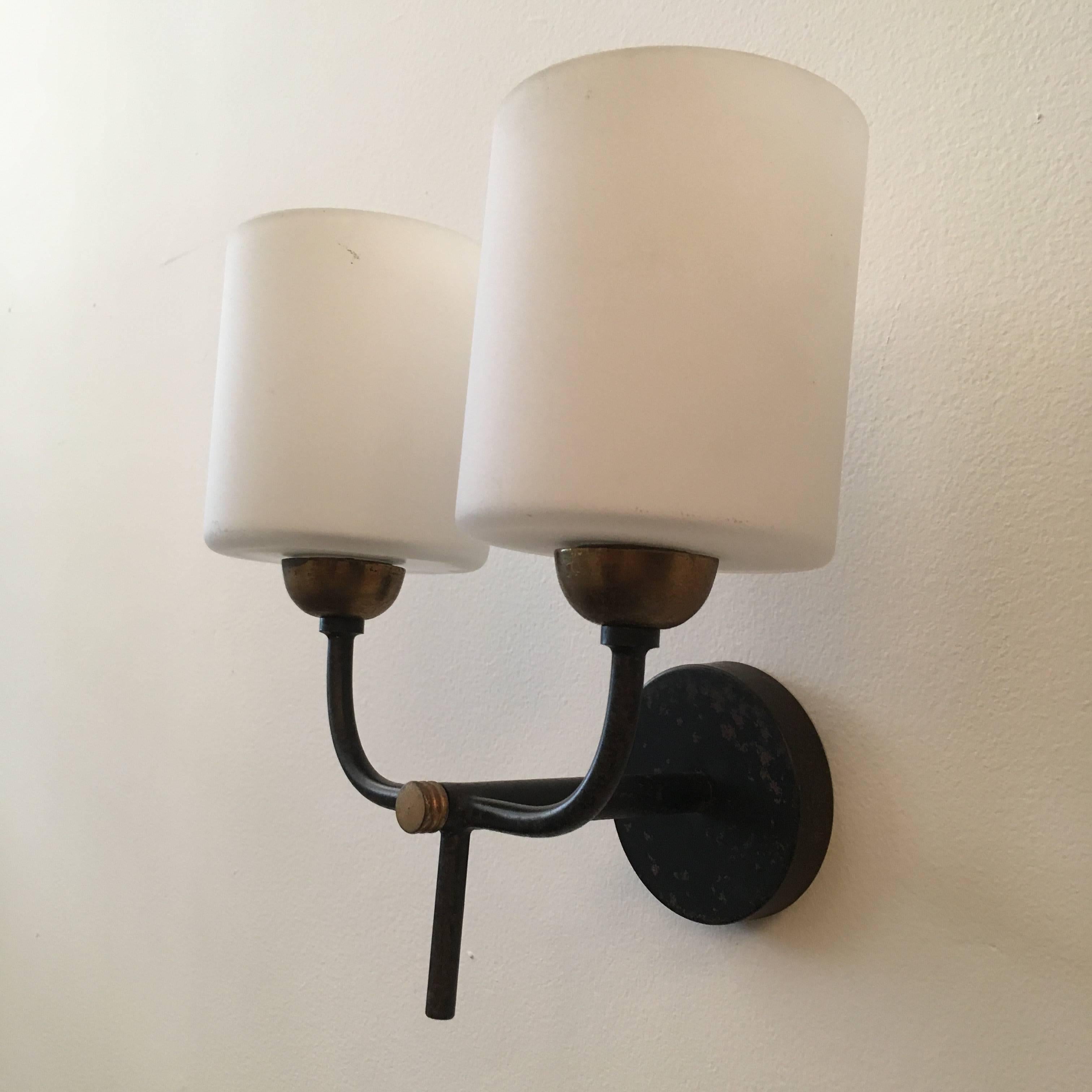 An original pair of French, 1960s sconces by Arlus. The wall lights are composed of black enamel and aged brass with white glass shades. Rewired.