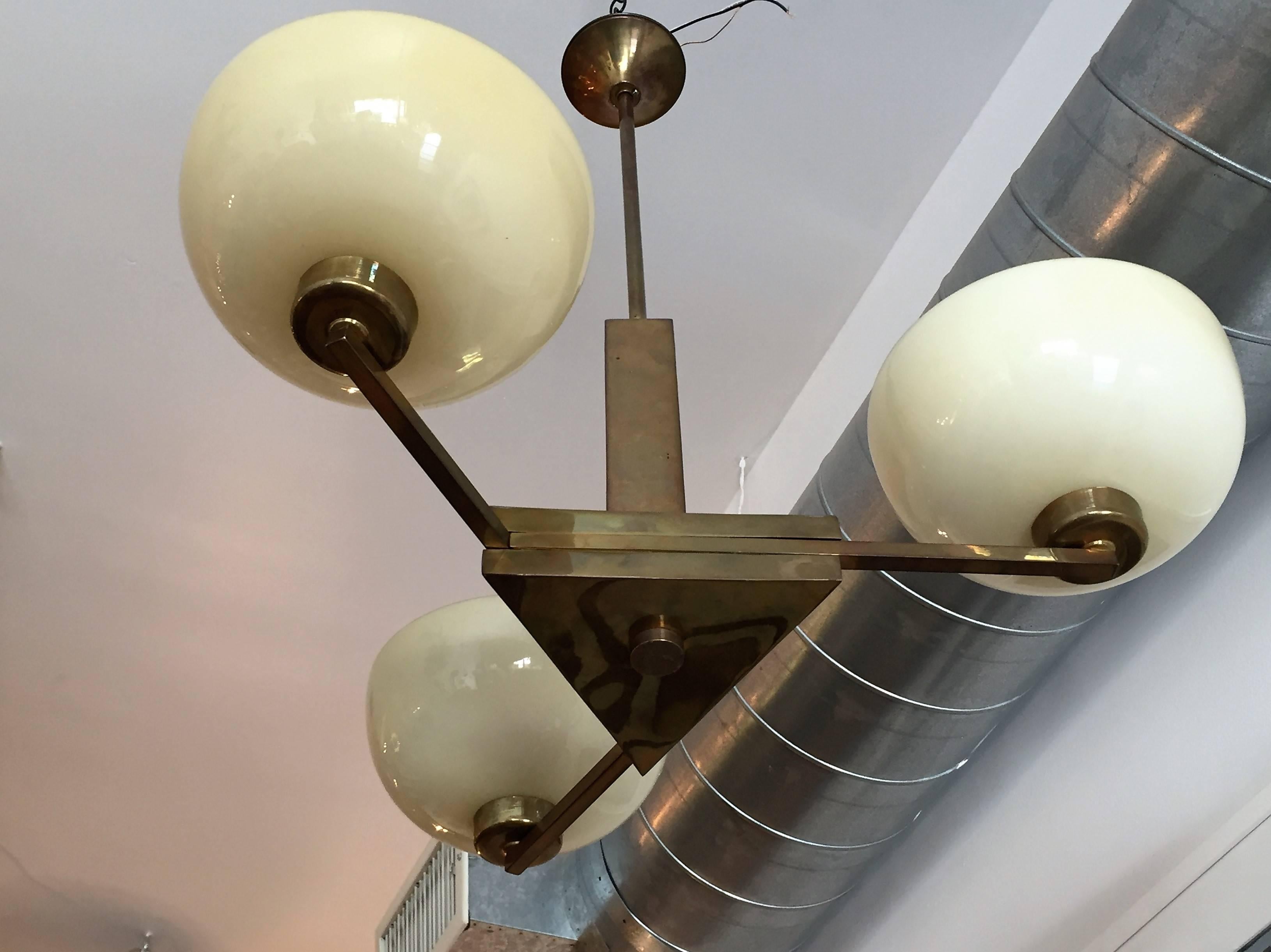 A rare original 1920s German Bauhaus simple modern pendant. The chandelier is composed of an aged polished brass triangular body with three straight rectangular arms holding large light custard glass bowl shades. Newly rewired.