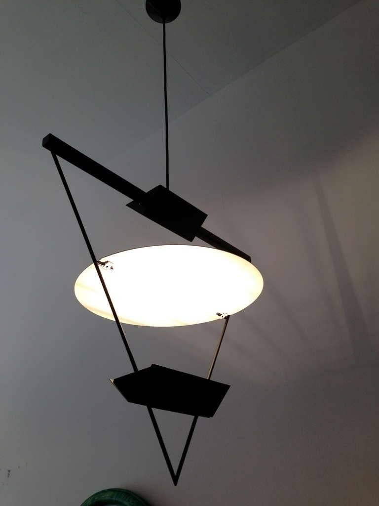 A great period 1980s black and white geometrical pendant light composed of a triangular matte black enameled fixture and a circular white diffuser shade.