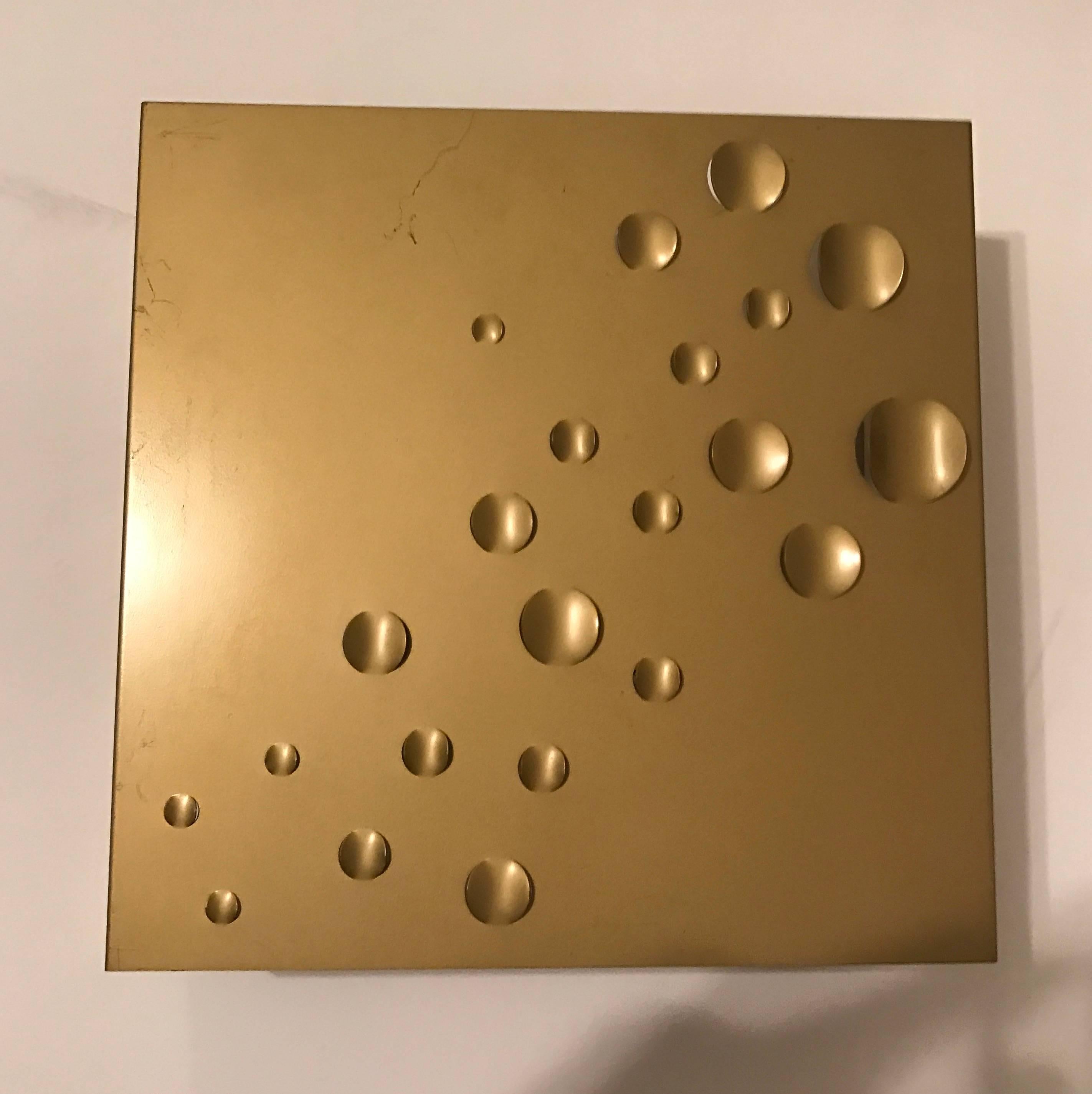 A great 1960s Space Age "rain drops" wall light by Dutch maker, RAAK . The square frame is composed of a matte gold steel enameled frame with perforated decorative indents to emit light as well as an open bottom and top.
Two standard