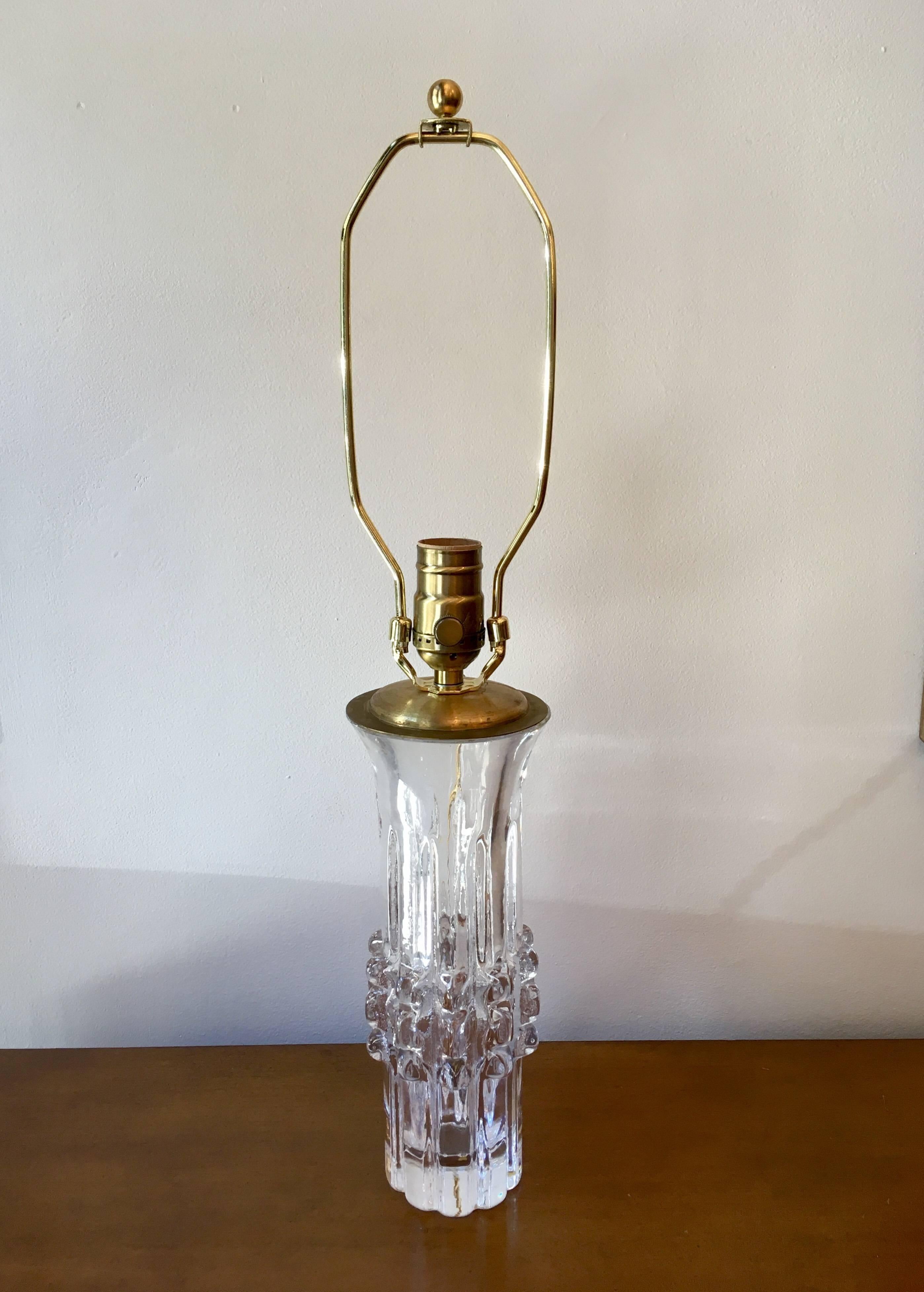 A pair of sparkling clear glass lamps with ridged sculptural elements and brass hardware by Bengt Edenfalk for Skruf, Scandinavian, circa 1960s. Signed.
Height of base to bottom of the socket, 11.5