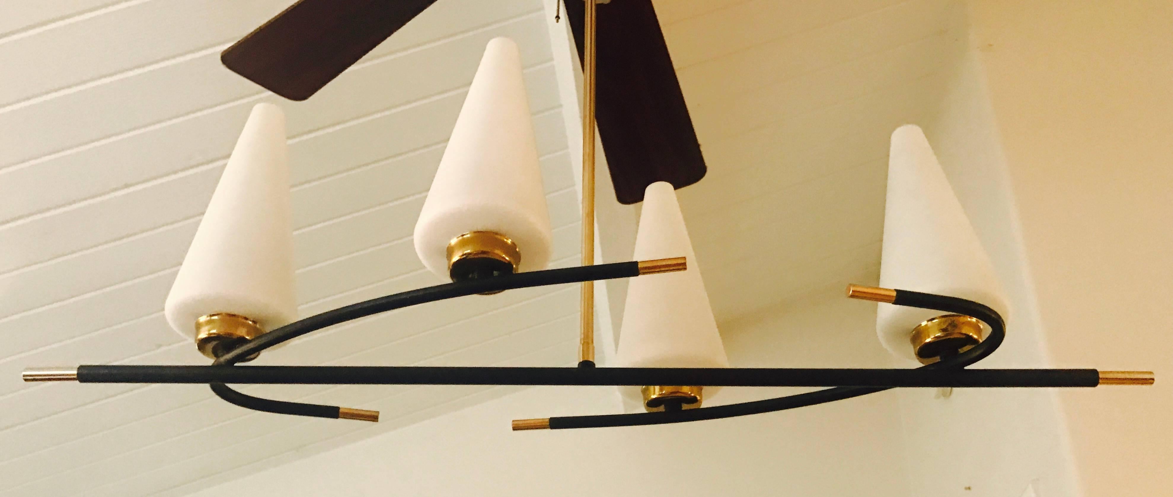 An original 1960s French chandelier composed of a curving matte black enamel and polished brass frame with four white glass conical shades. Newly rewired.