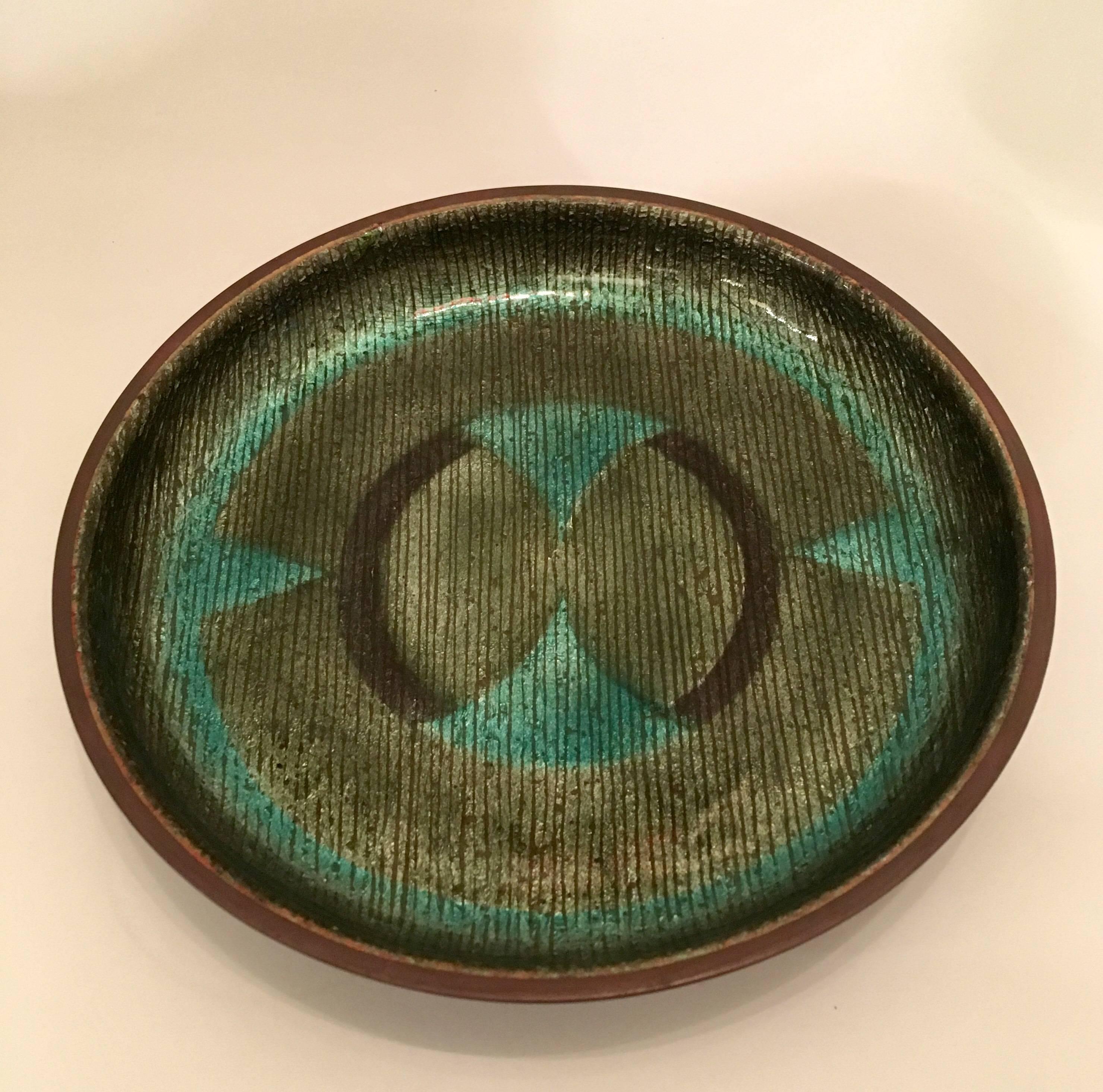 A 1960s handmade enamel over copper with an abstract design in colors of black, and olive and teal green. Signed.
