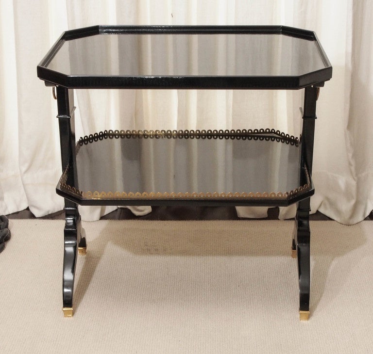 Two elegant two-tier side tables attributed to Maison Jansen in high gloss black lacquer; bronze details at the pierced gallery rail, sabots, and side circular 