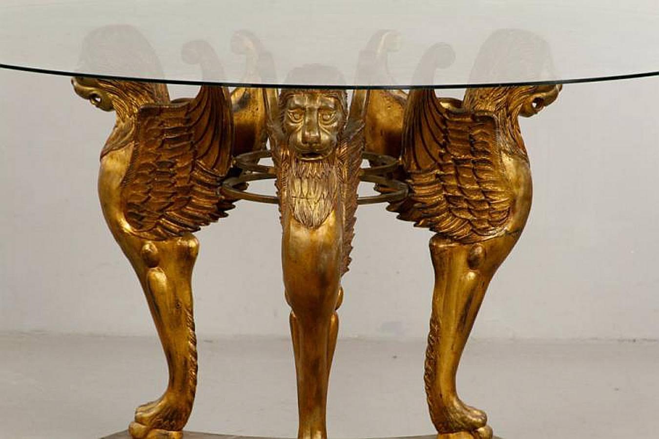 An exceptionally designed center table that could double as a dining table. Spectacular winged griffins gilded in 22-karat gold. These figures are mounted upon a tripartite embossed leather covered platform base detailed with gilded decoration on