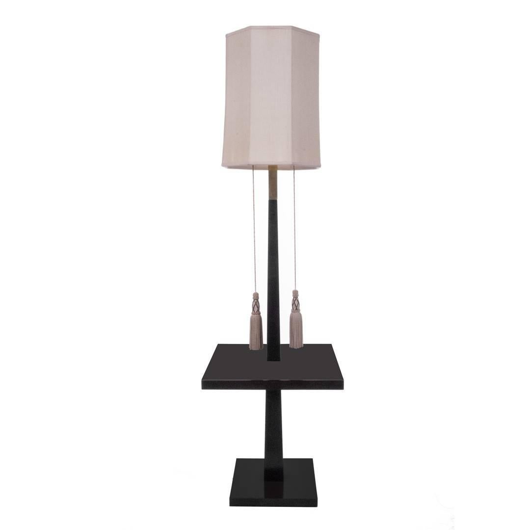 An ebonized wood floor lamp by Tommi Parzinger. Signed, USA, circa 1940. Features a bold square base, with brass hardware and original tassels and silk shade.
               
        