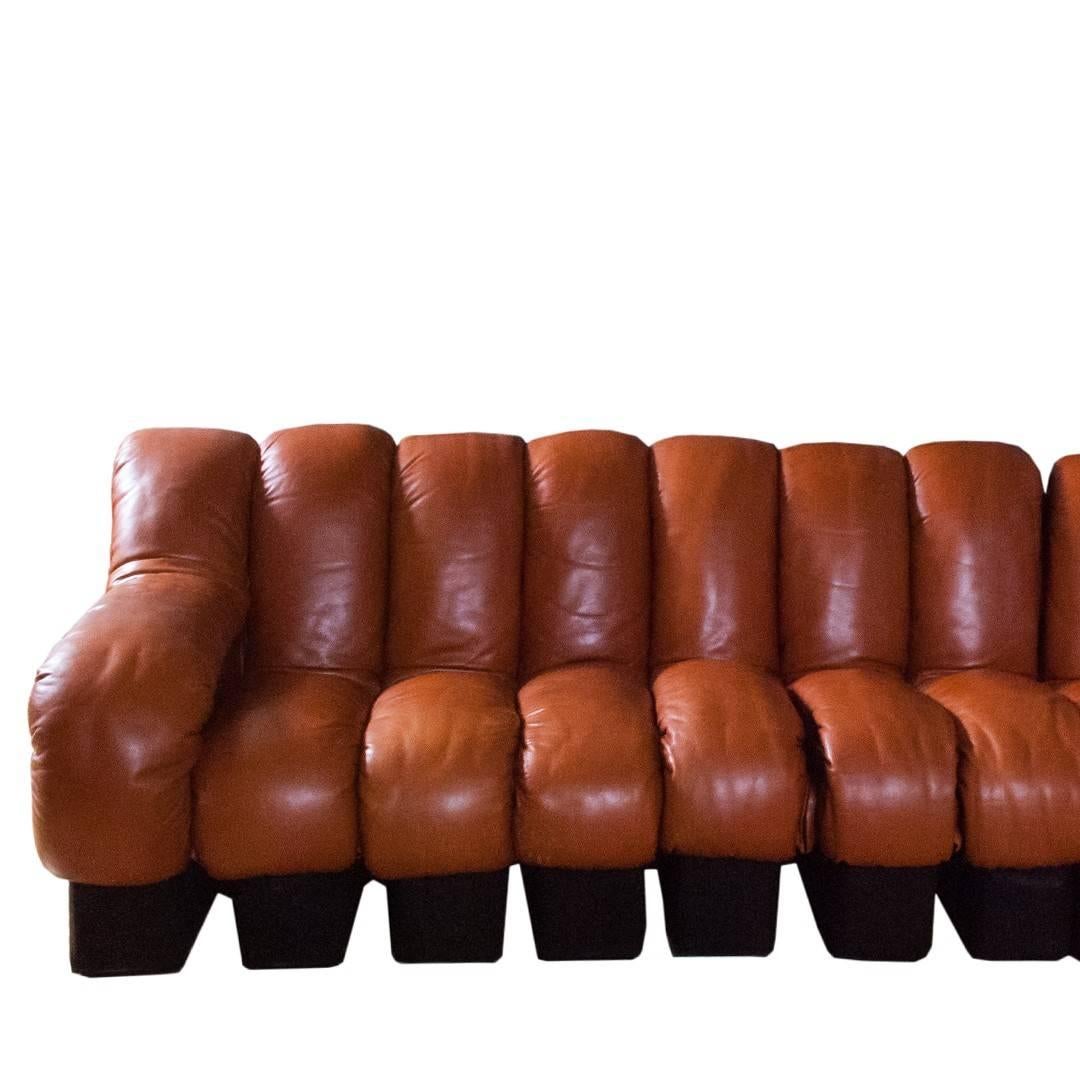 A model DS600 non-stop sofa in cognac channeled leather with brown fabric base by De Sede for Stendig, Switzerland, circa 1970. Features a modular design with 18 sections that are fully interchangeable.
