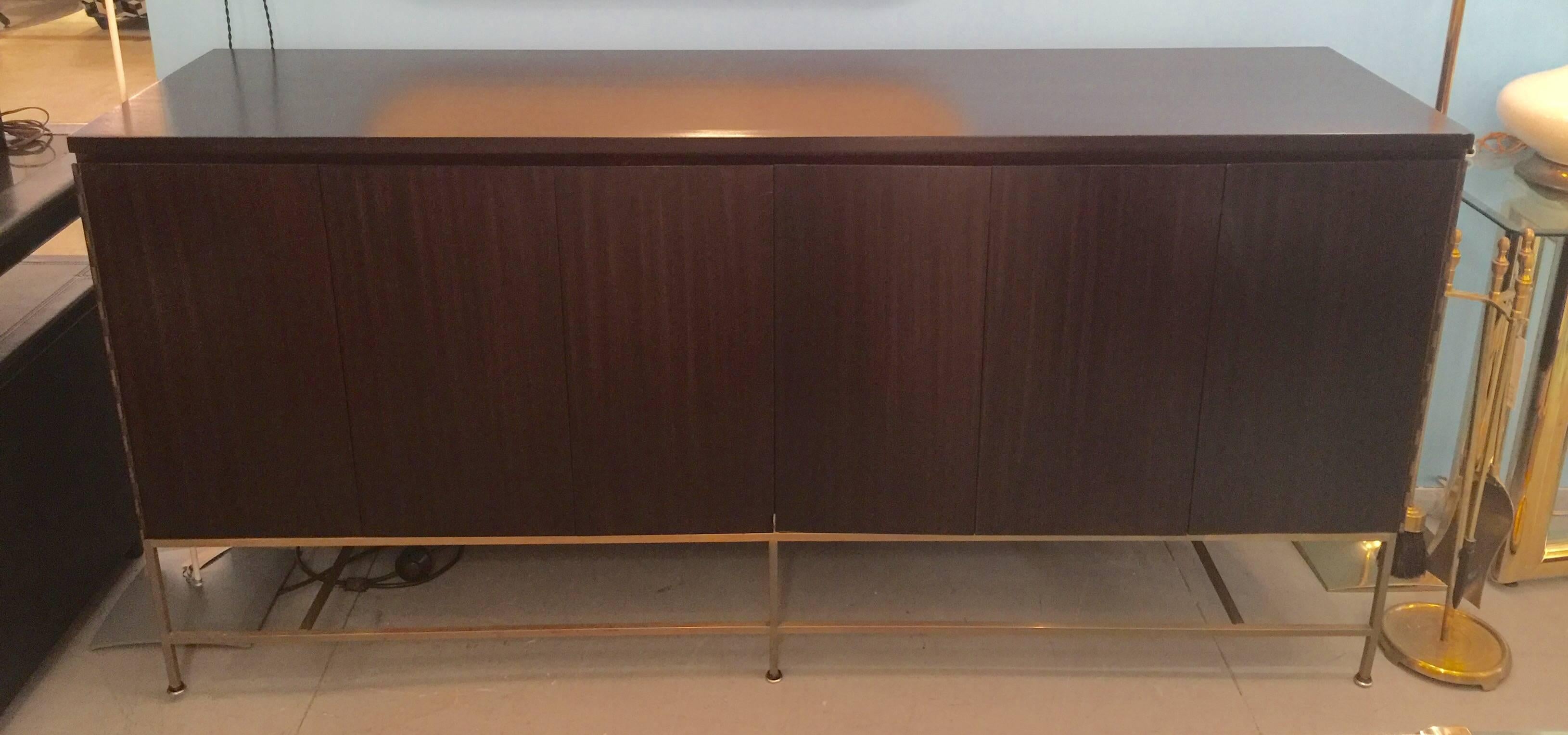 A folding-drawer mahogany credenza with brass base by Paul McCobb for Calvin Group. USA, circa 1950. Features interior shelves and drawers. Finish is espresso / dark brown stain.